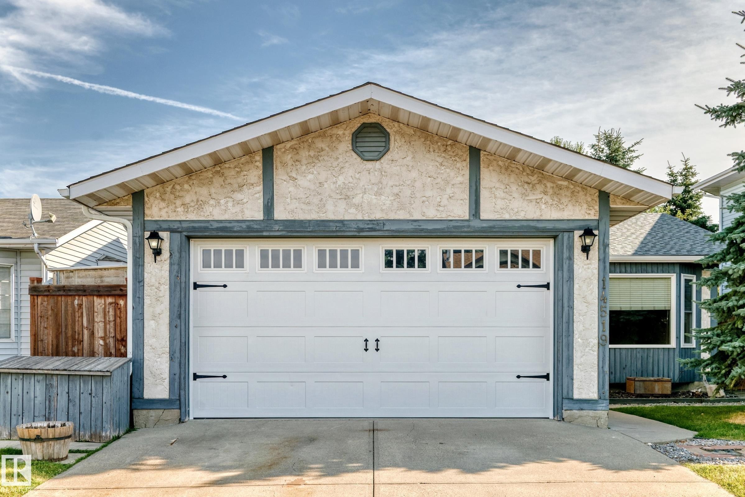 Garage exterior featuring a stucco finish with timber-style trim - 14519 32 Street Nw, Edmonton, AB