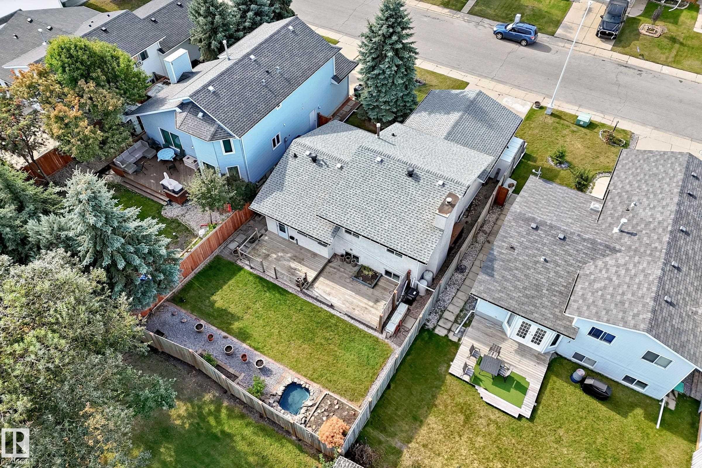 Expansive backyard featuring a manicured lawn, multi-level wood deck, and mature trees - 14519 32 Street Nw, Edmonton, AB