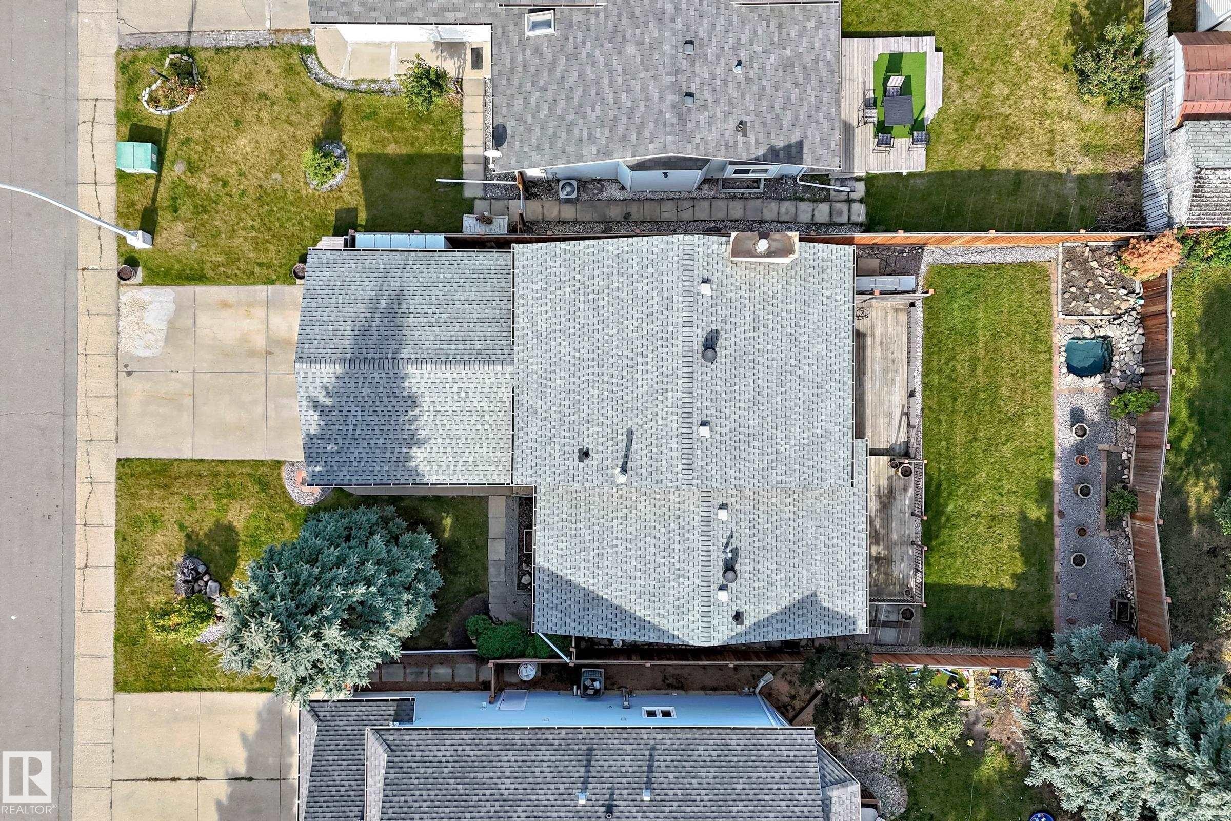 Shingle roof property with an expansive concrete driveway, a front lawn with mature trees, and a rear deck leading to a manicured lawn and a small water feature - 14519 32 Street Nw, Edmonton, AB