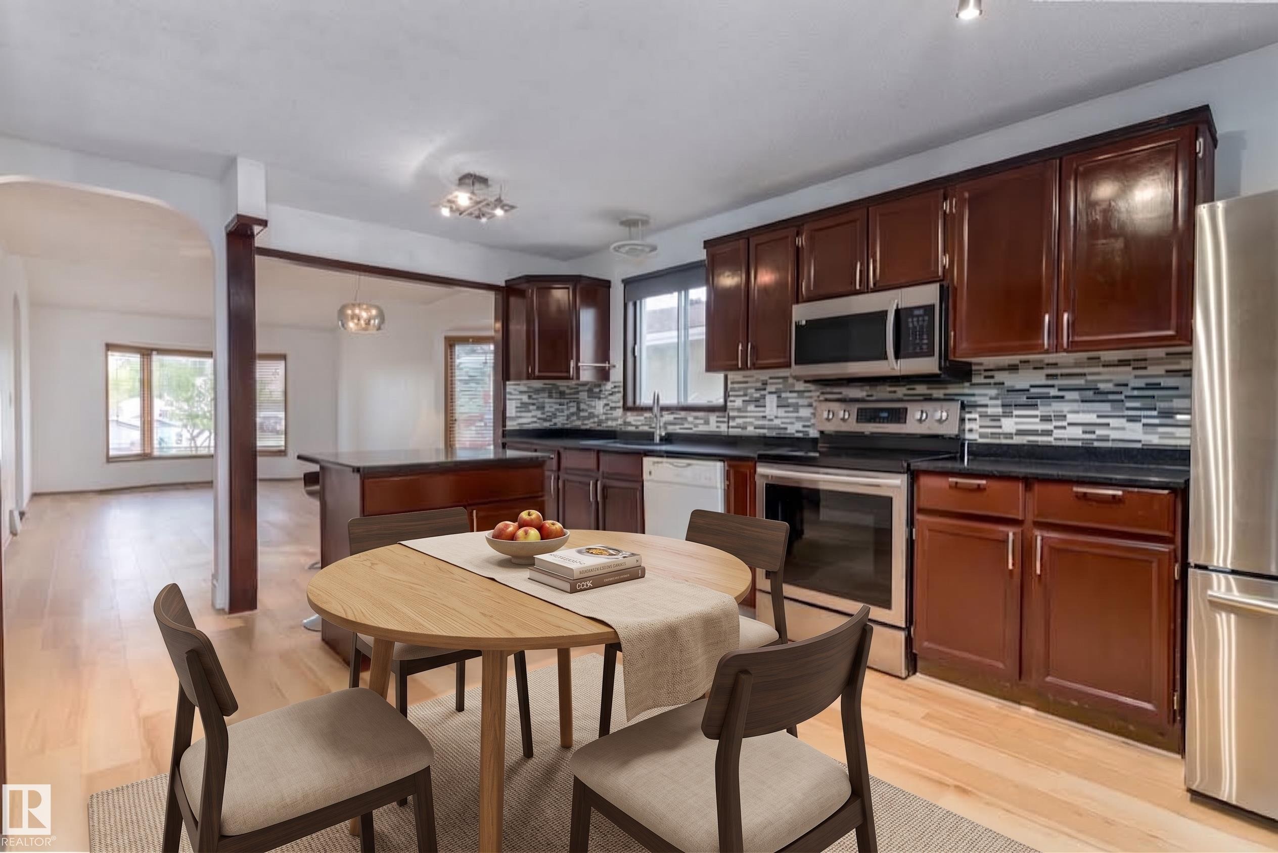 Kitchen featuring dark wood cabinetry, stainless steel appliances, mosaic tile backsplash, and light wood-finish flooring - 18739 72 Avenue Nw, Edmonton, AB