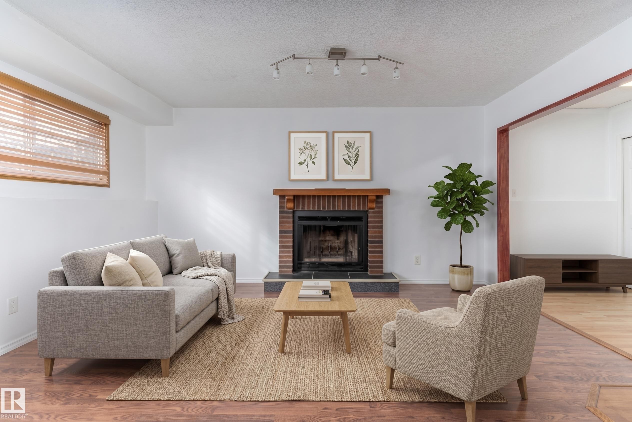 Brick fireplace with wood mantel, track lighting fixture, wood-finish flooring, and window with wood blinds - 18739 72 Avenue Nw, Edmonton, AB