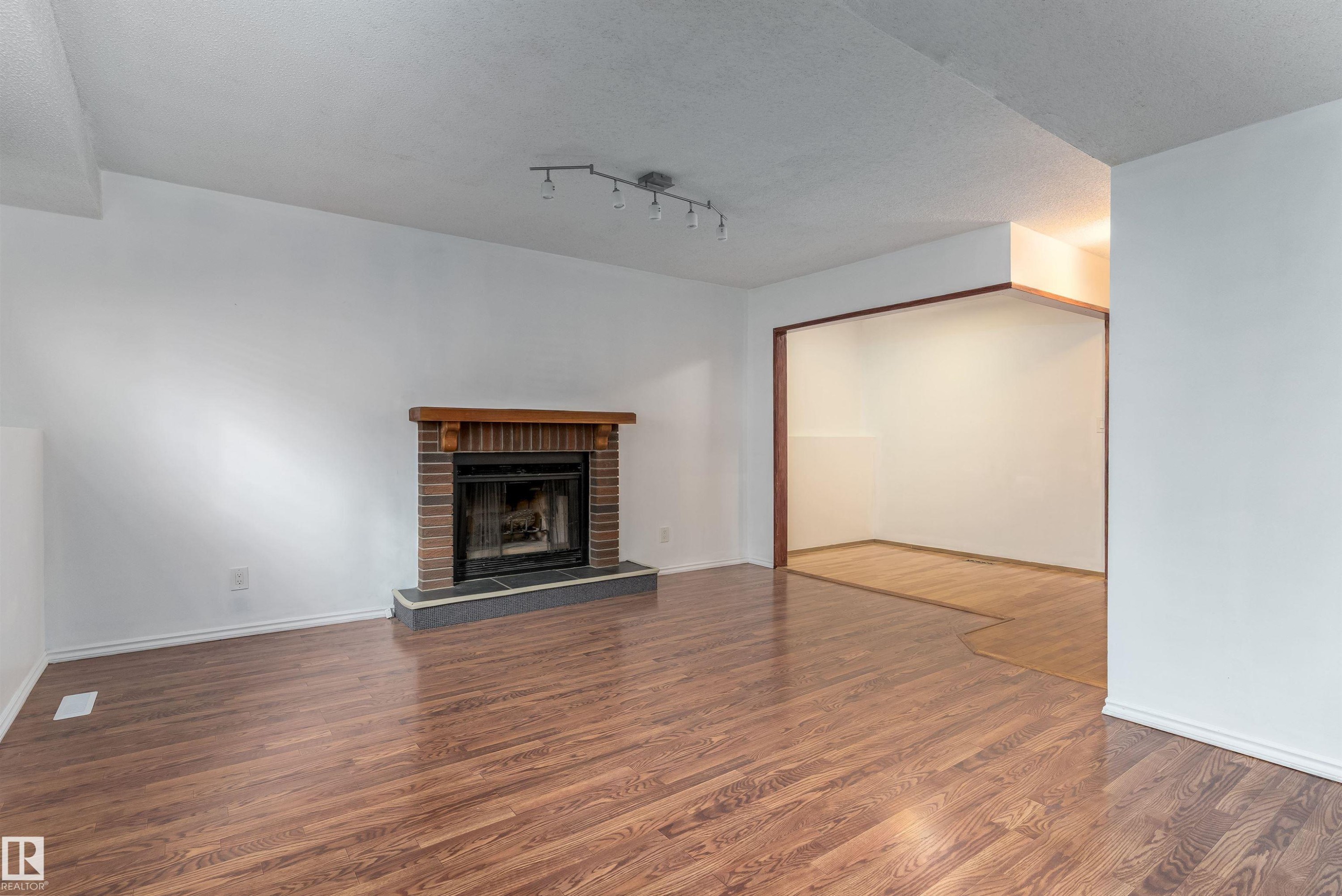 Brick fireplace with a wood mantel and stone hearth - 18739 72 Avenue Nw, Edmonton, AB