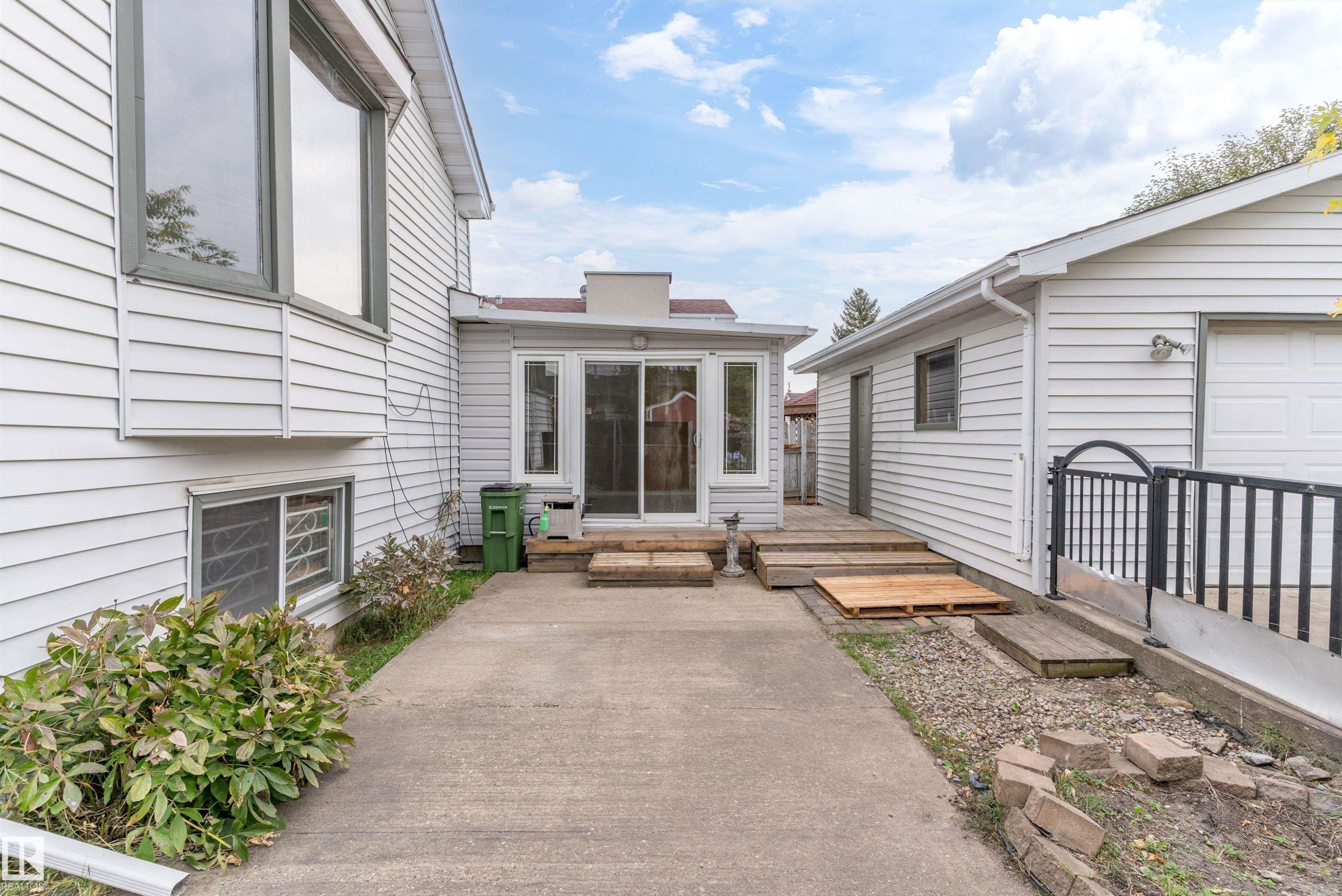 White horizontal siding on the exterior, featuring a sunroom with sliding glass doors and an attached garage - 18739 72 Avenue Nw, Edmonton, AB