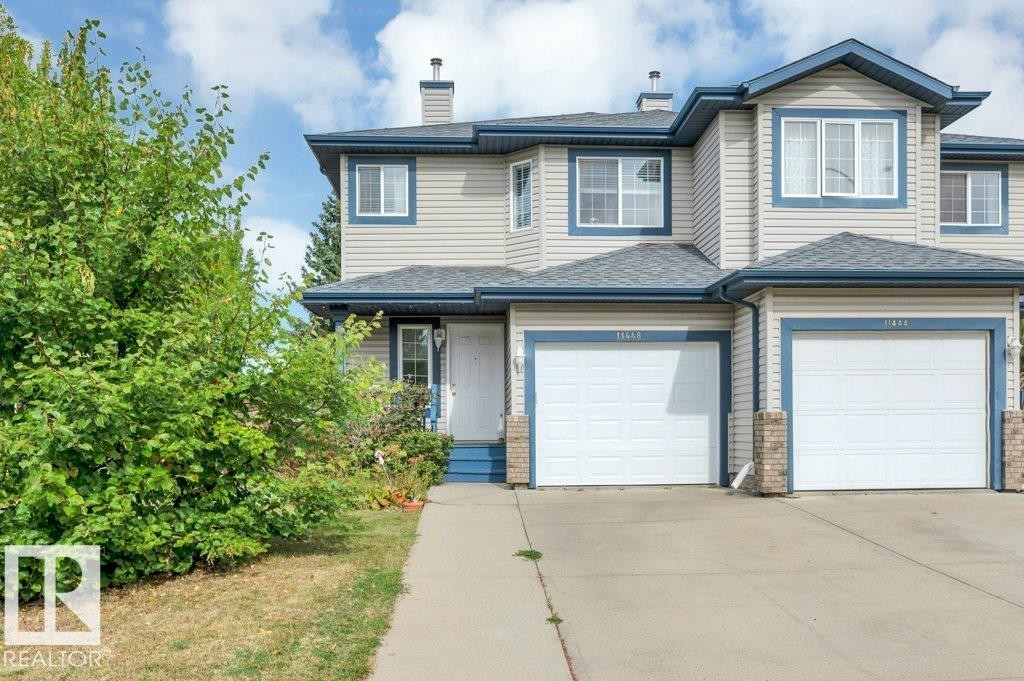 Two-story exterior with light-colored siding, contrasting blue trim, multiple windows, and a single attached garage - 11448 169 Avenue Nw, Edmonton, AB