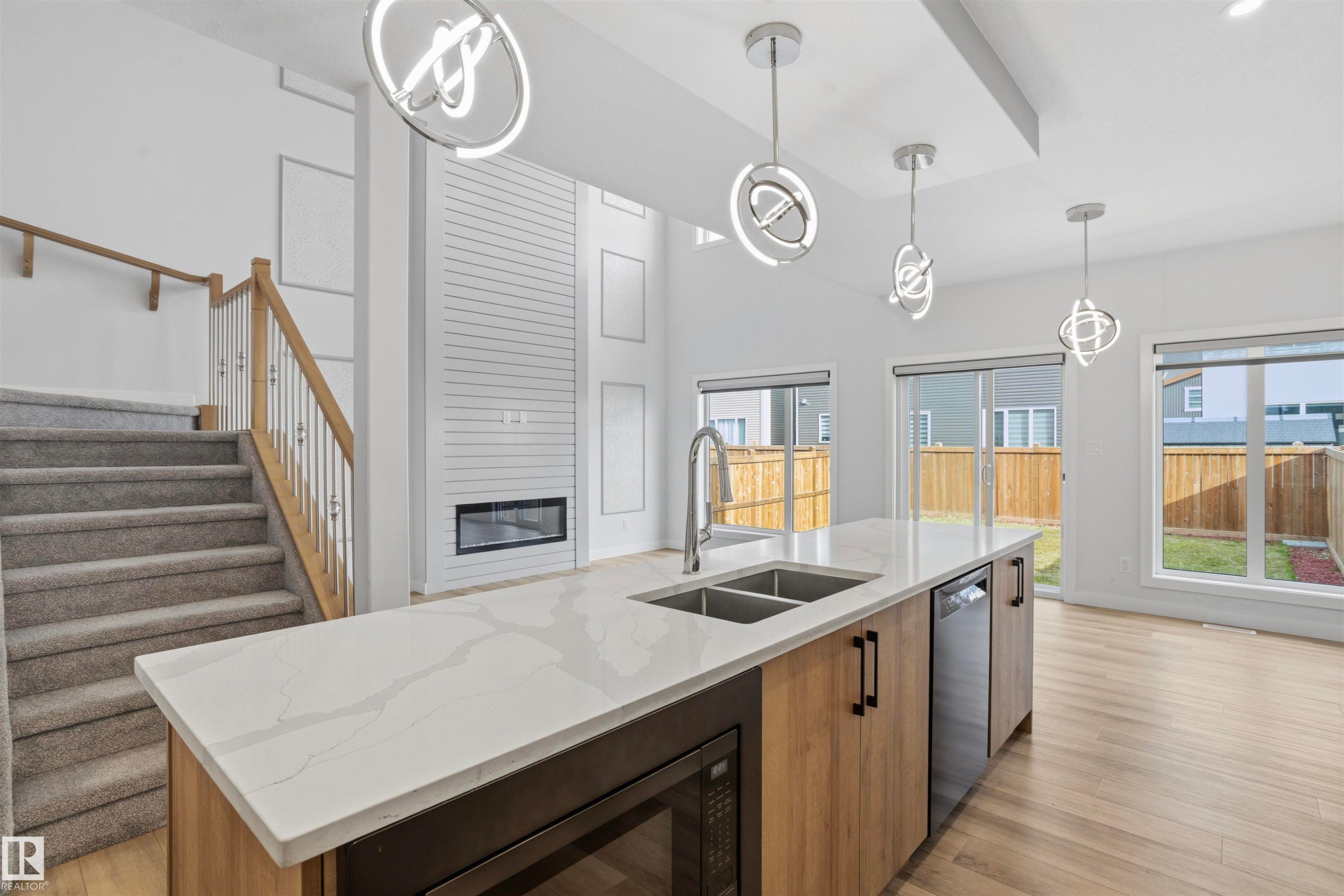 Kitchen island featuring a stone countertop, under-mount dual-basin sink, and wood-finish cabinetry - 2045 209A St Nw, Edmonton, AB
