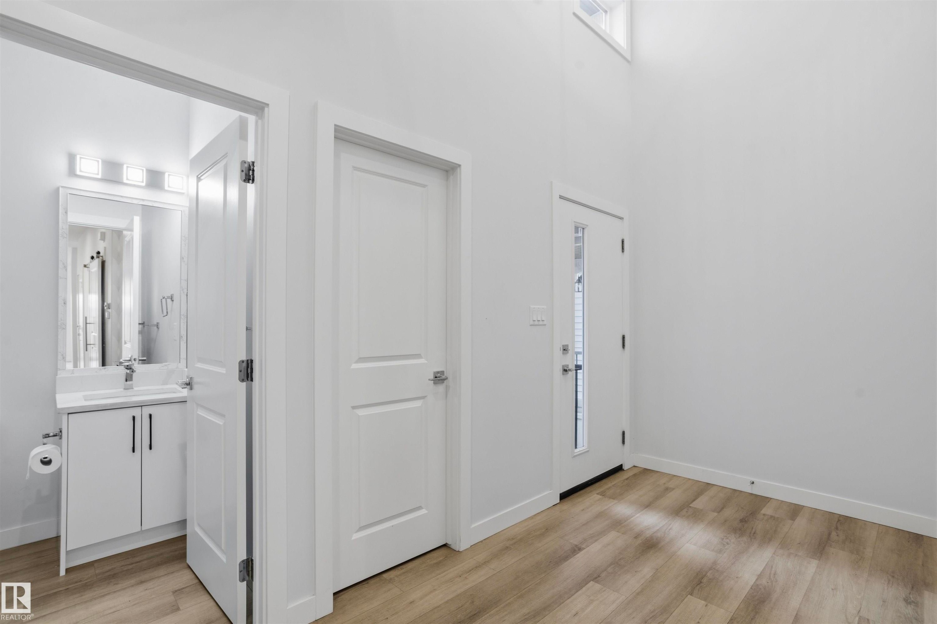 Entryway featuring wood-finish flooring, high ceilings, and a door with a vertical glass pane - 2045 209A St Nw, Edmonton, AB