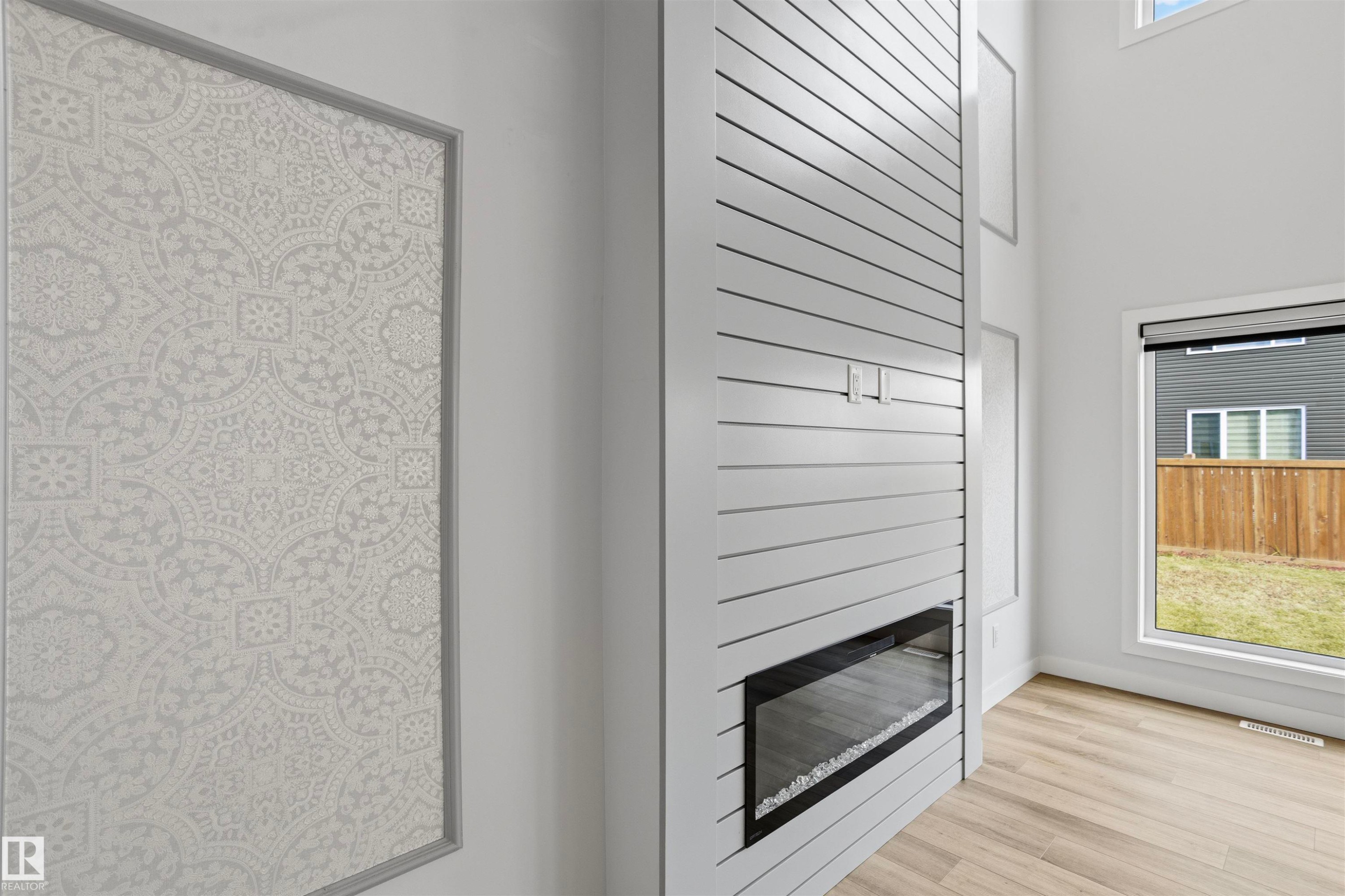 Floor-to-ceiling shiplap fireplace surround with a linear electric insert, wood-finish flooring, high ceilings, and decorative wall paneling - 2045 209A St Nw, Edmonton, AB