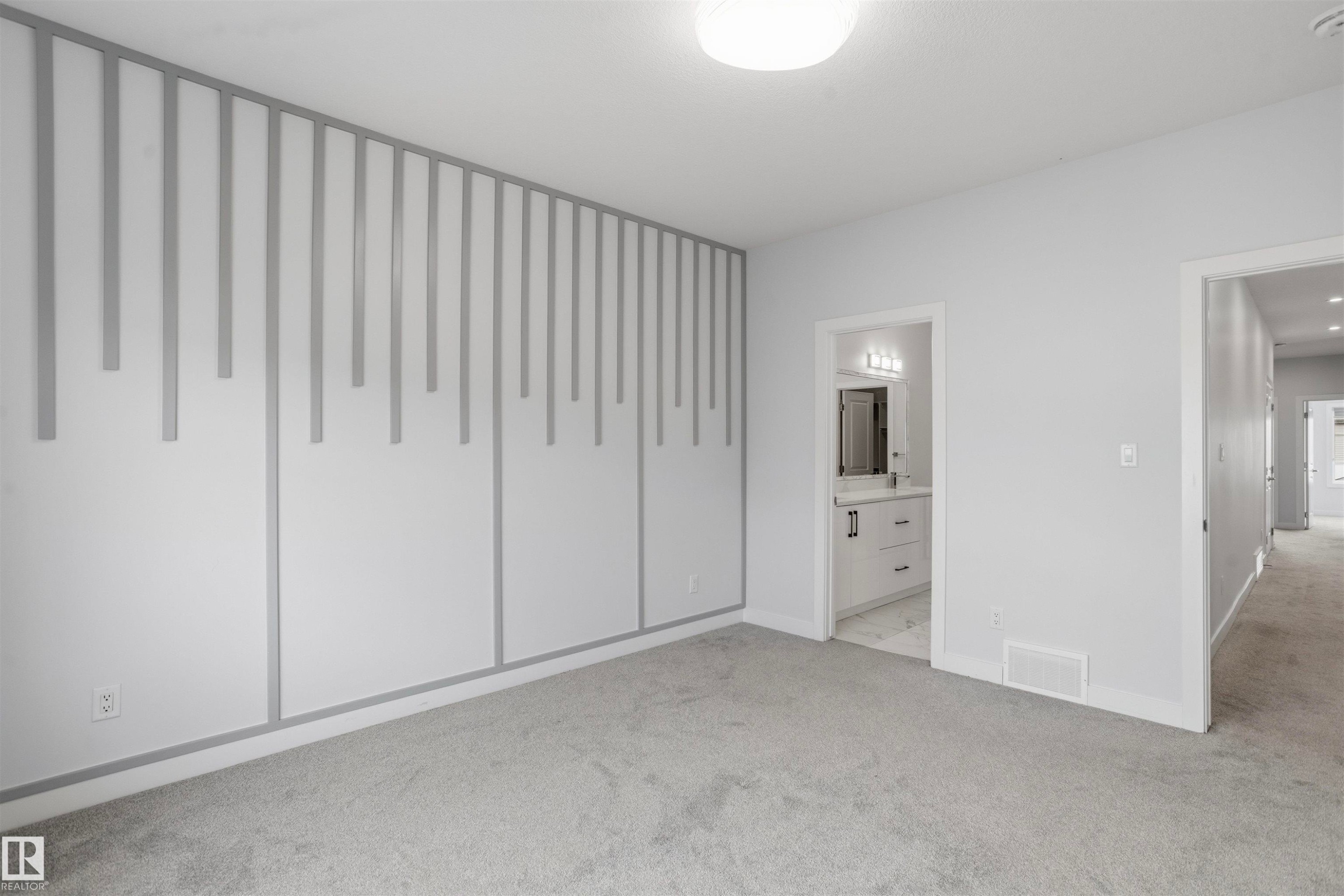 Neutral interior featuring wall-mounted slat accent paneling, carpeting, flush-mount ceiling lighting, and a white vanity with hardware in an attached space - 2045 209A St Nw, Edmonton, AB