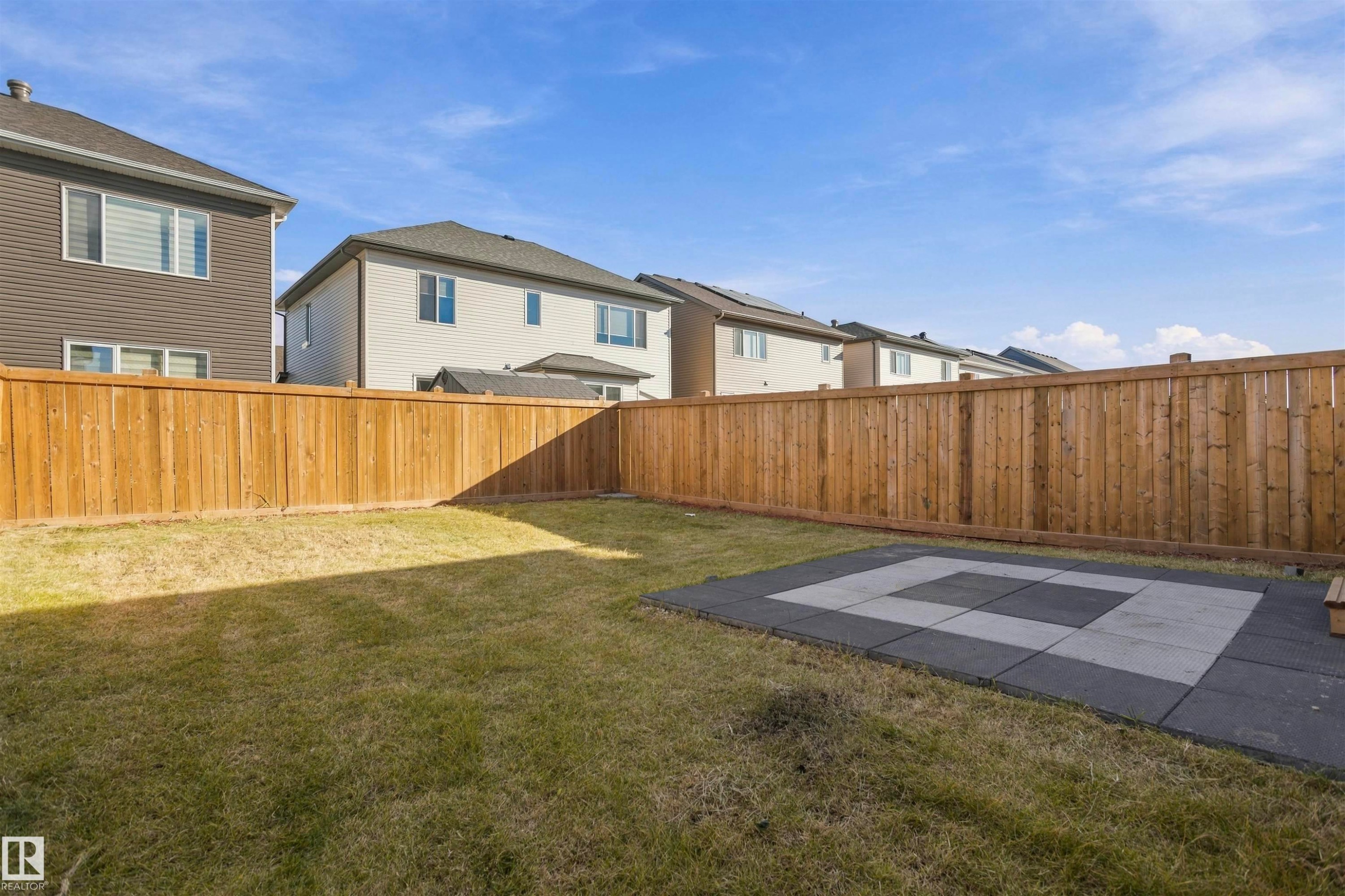 Fenced rear yard featuring a grass lawn and a paved patio area - 2045 209A St Nw, Edmonton, AB