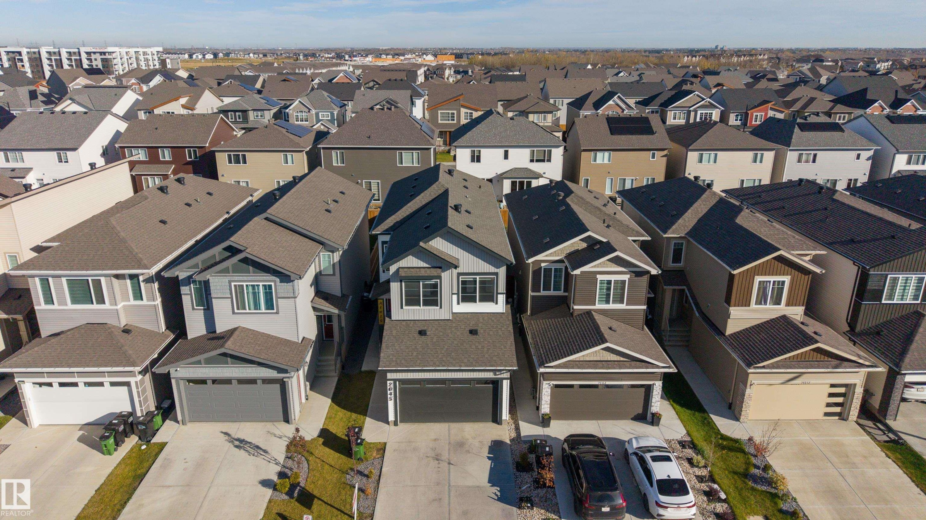 Aerial view featuring multi-story residential structures with pitched asphalt shingle roofing, concrete driveways, and attached multi-car garages - 2045 209A St Nw, Edmonton, AB