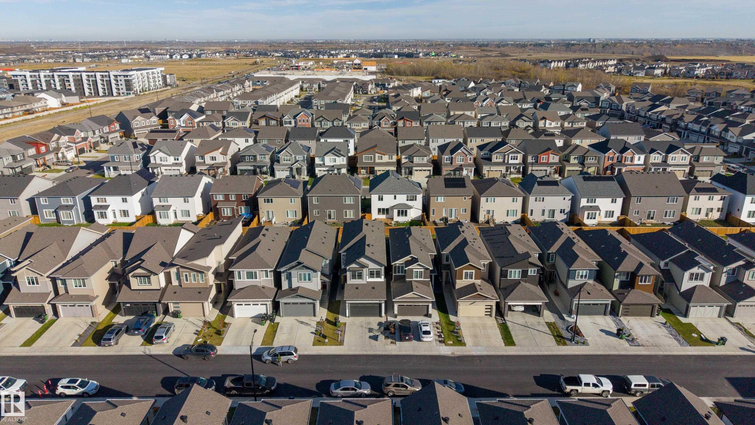 Aerial perspective of a suburban neighborhood featuring residential homes with multi-gabled rooflines, attached garage structures, paved private driveways, and consistent sidewalk infrastructure - 2045 209A St Nw, Edmonton, AB