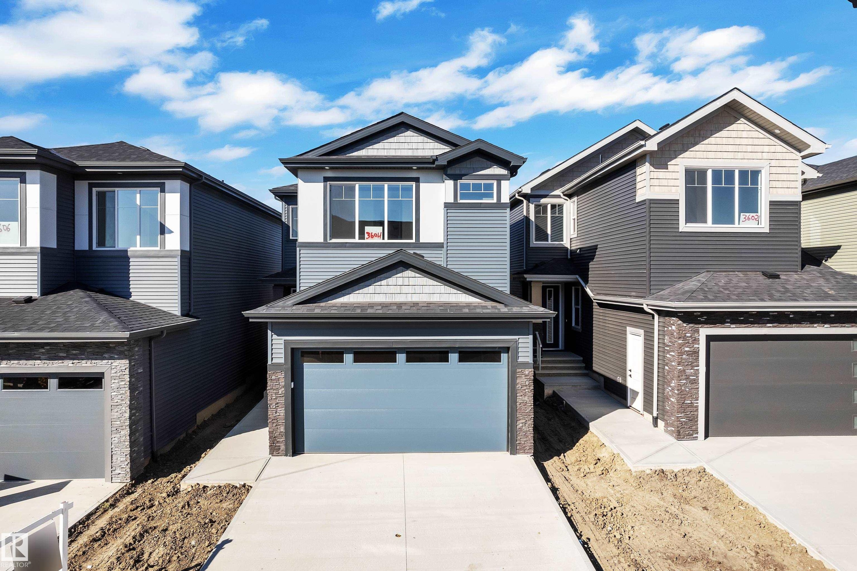 Contemporary residential exterior featuring a multi-tone facade, attached garage, and a concrete driveway - 3604 44 Avenue, Beaumont, AB