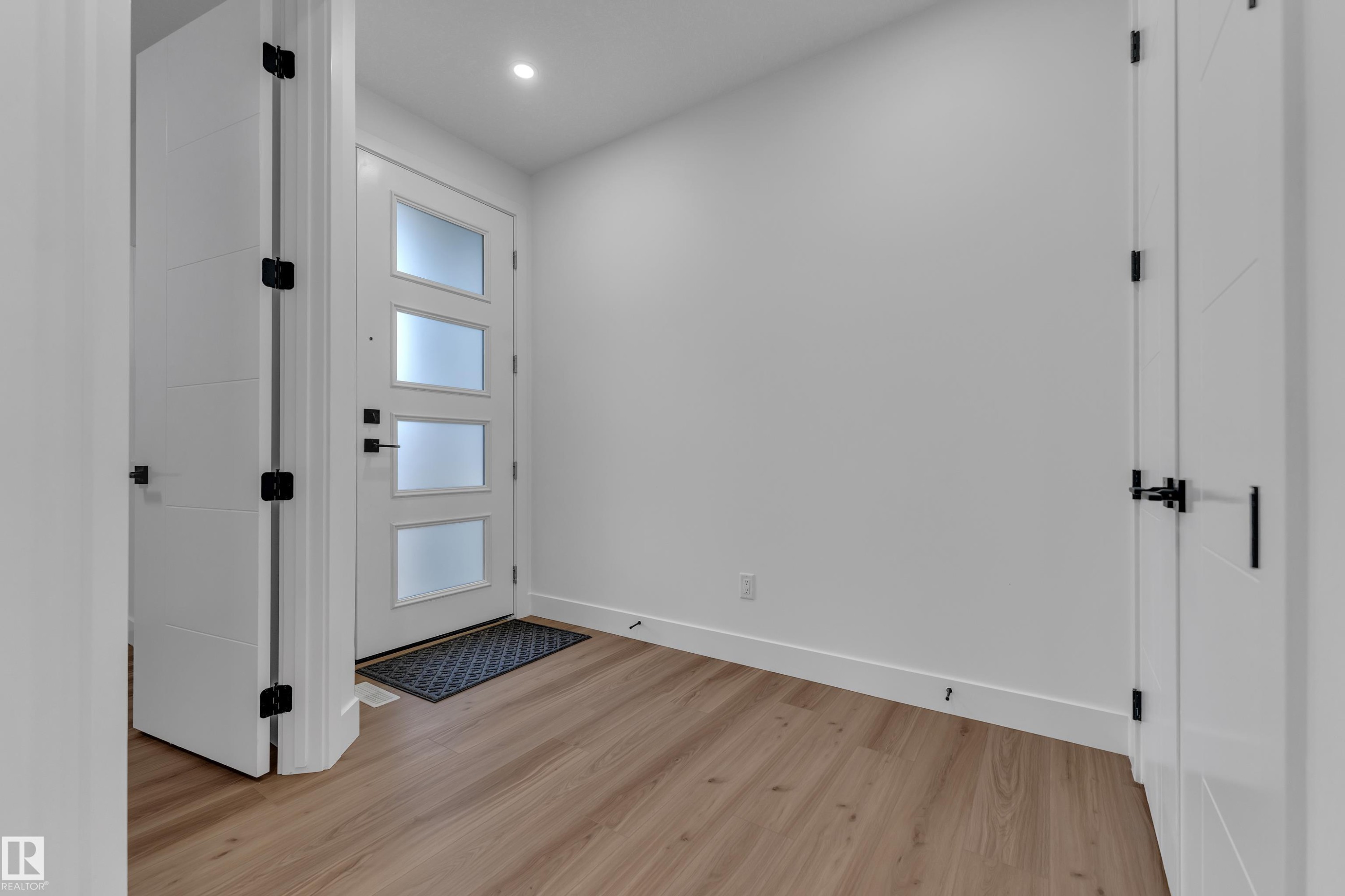 Entryway featuring a white door with frosted glass panels, wood-finish flooring, and recessed lighting - 3604 44 Avenue, Beaumont, AB