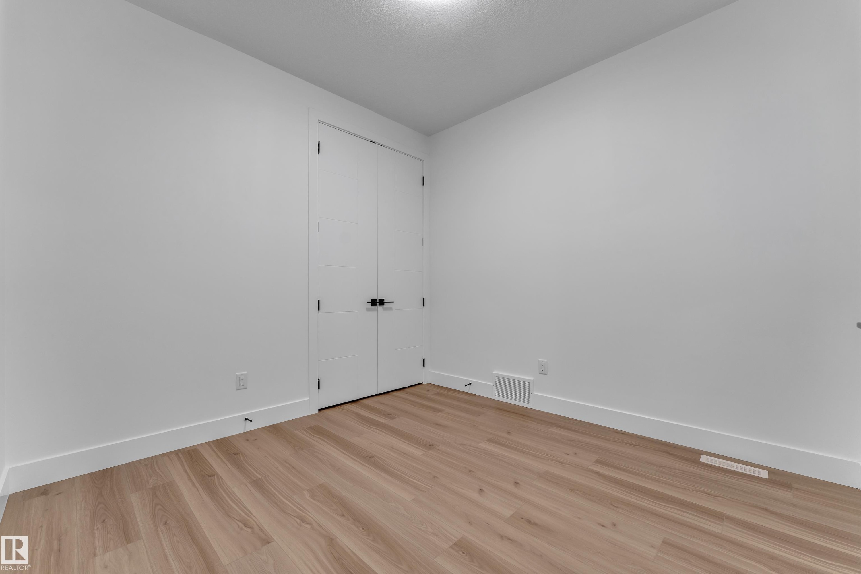 Wood-finish flooring, white walls, white trim, recessed ceiling light, and double closet doors with dark hardware - 3604 44 Avenue, Beaumont, AB