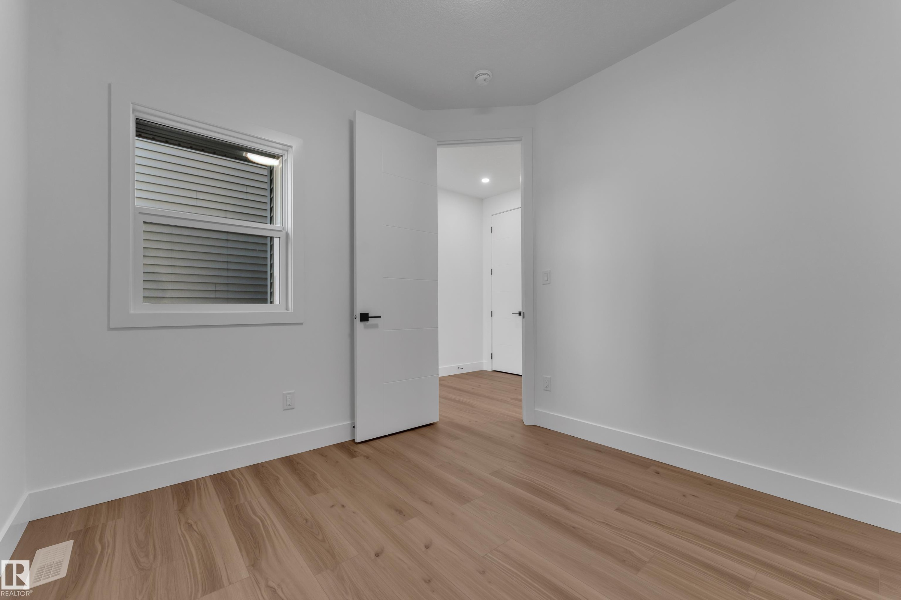 Wood-finish flooring, white walls, white trim, white interior doors, and a window with horizontal blinds - 3604 44 Avenue, Beaumont, AB