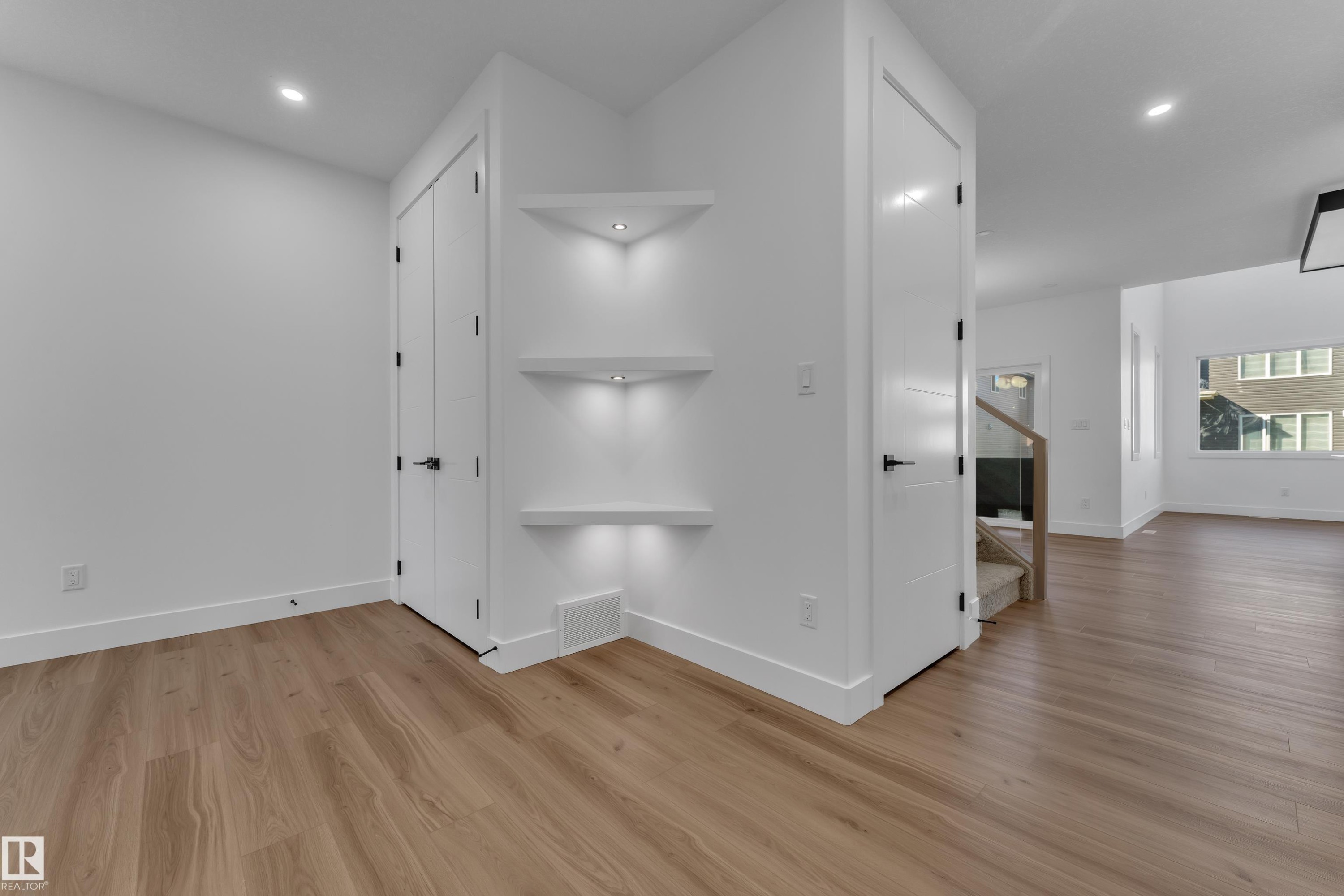 Wood-finish flooring, recessed lighting, built-in shelving with accent lighting, and white trim throughout - 3604 44 Avenue, Beaumont, AB