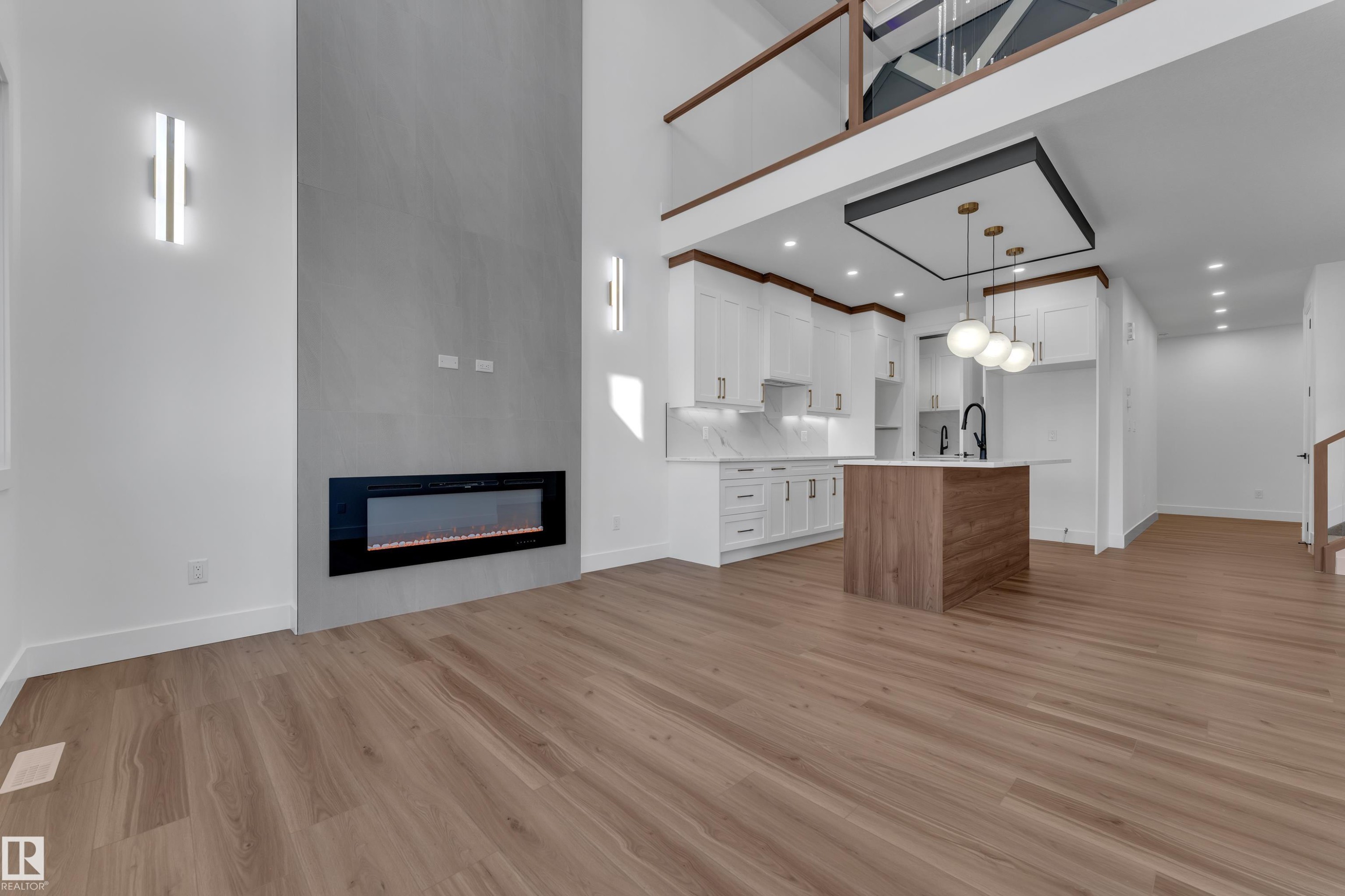 Open-concept living area featuring a modern fireplace, vaulted ceiling, and wood-finish flooring - 3604 44 Avenue, Beaumont, AB