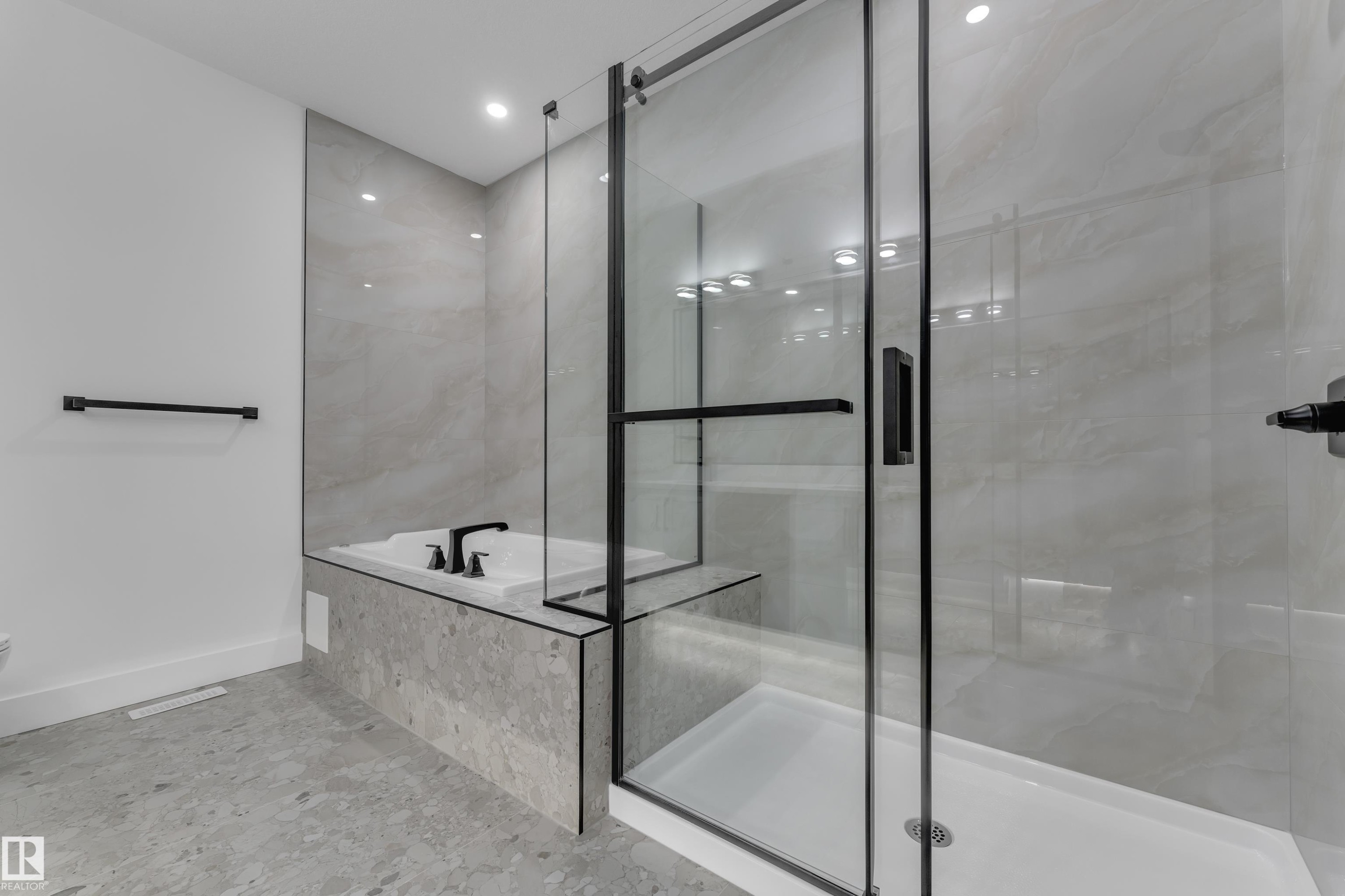 Walk-in shower with clear glass enclosure and black frame, featuring a built-in tub with matte black fixtures - 3604 44 Avenue, Beaumont, AB