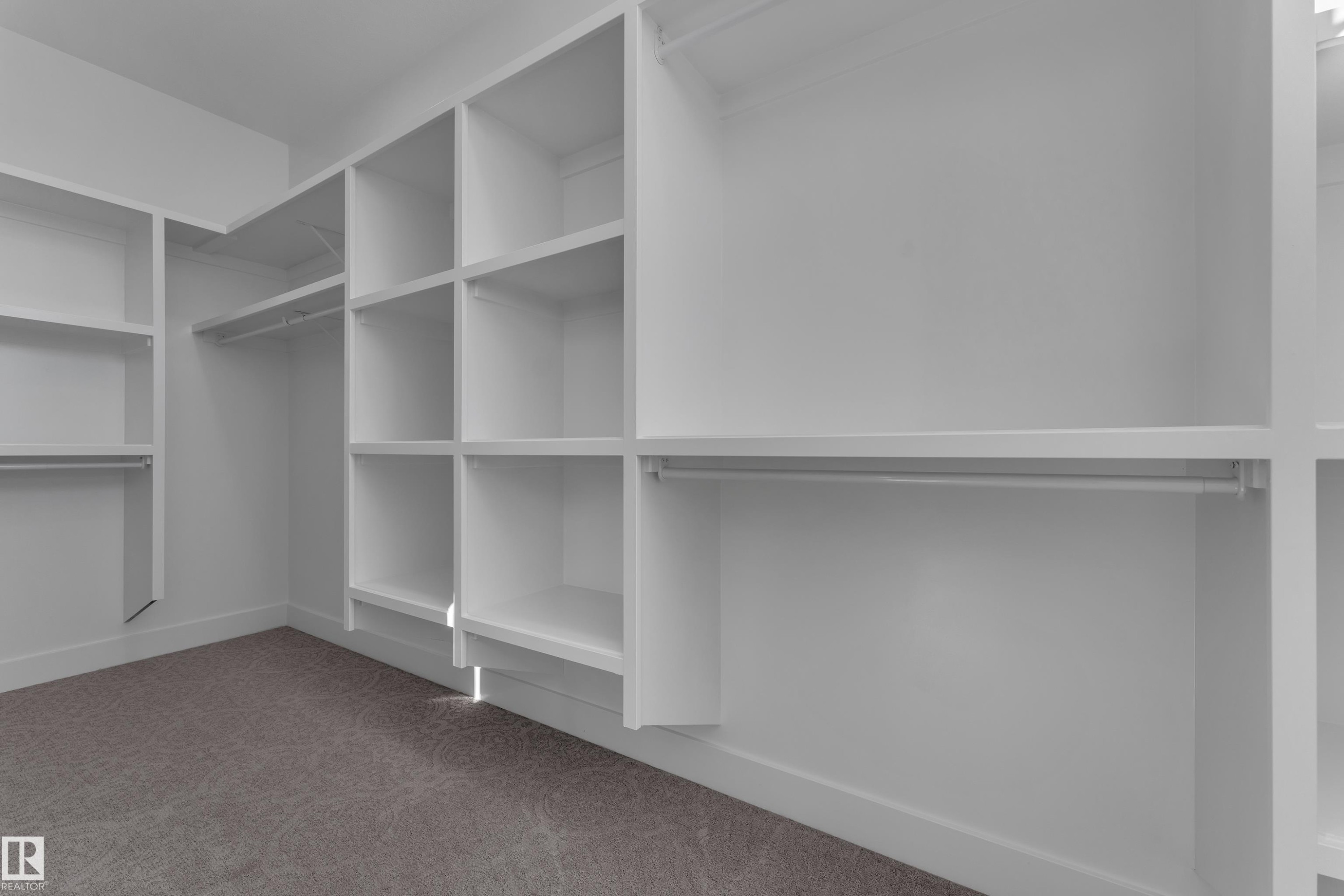 Custom closet system featuring white shelving units, multiple hanging rods, and built-in cubbies - 3604 44 Avenue, Beaumont, AB