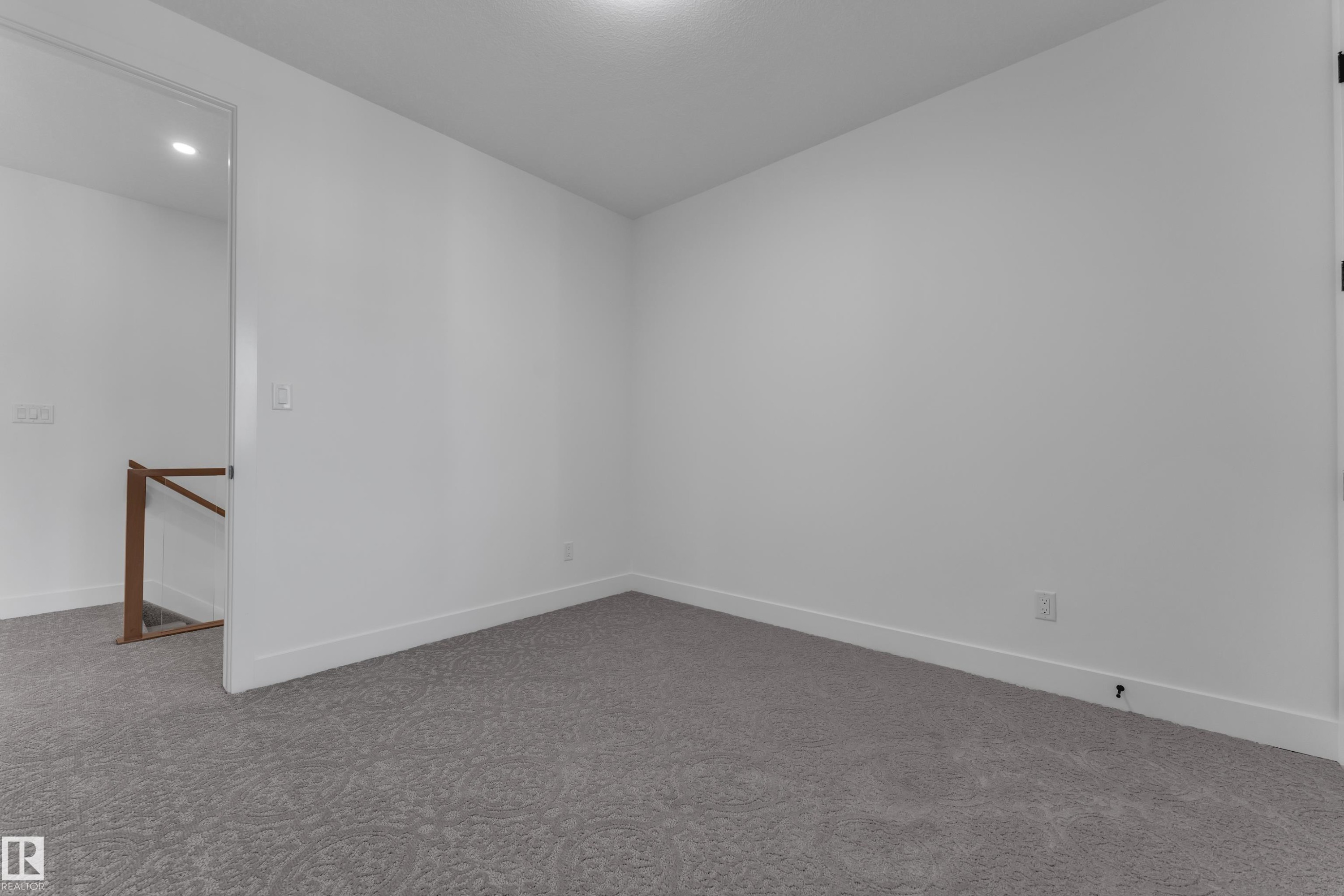 Recessed ceiling lighting, light gray patterned carpeting, white walls, and a wood handrail - 3604 44 Avenue, Beaumont, AB