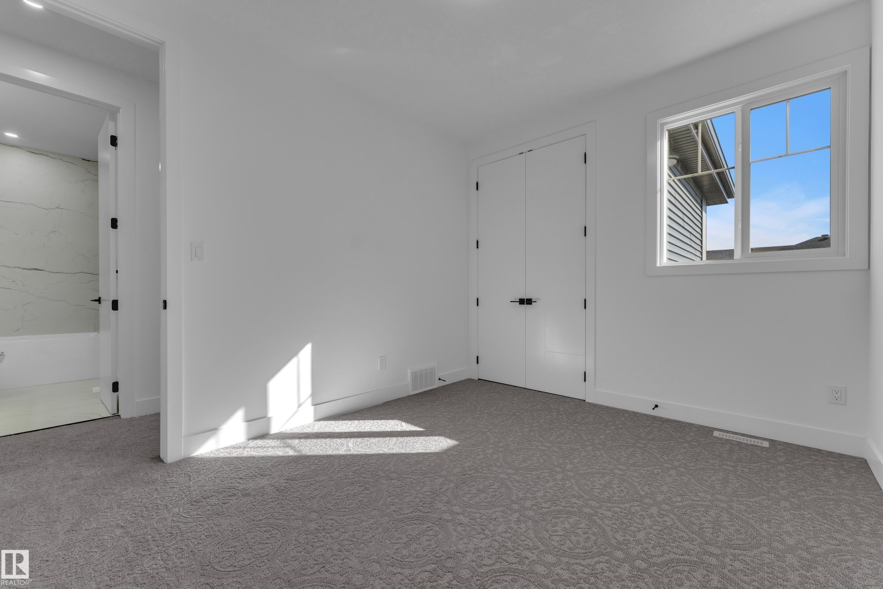 Bright interior with gray patterned carpeting, white walls, and a multi-pane window - 3604 44 Avenue, Beaumont, AB