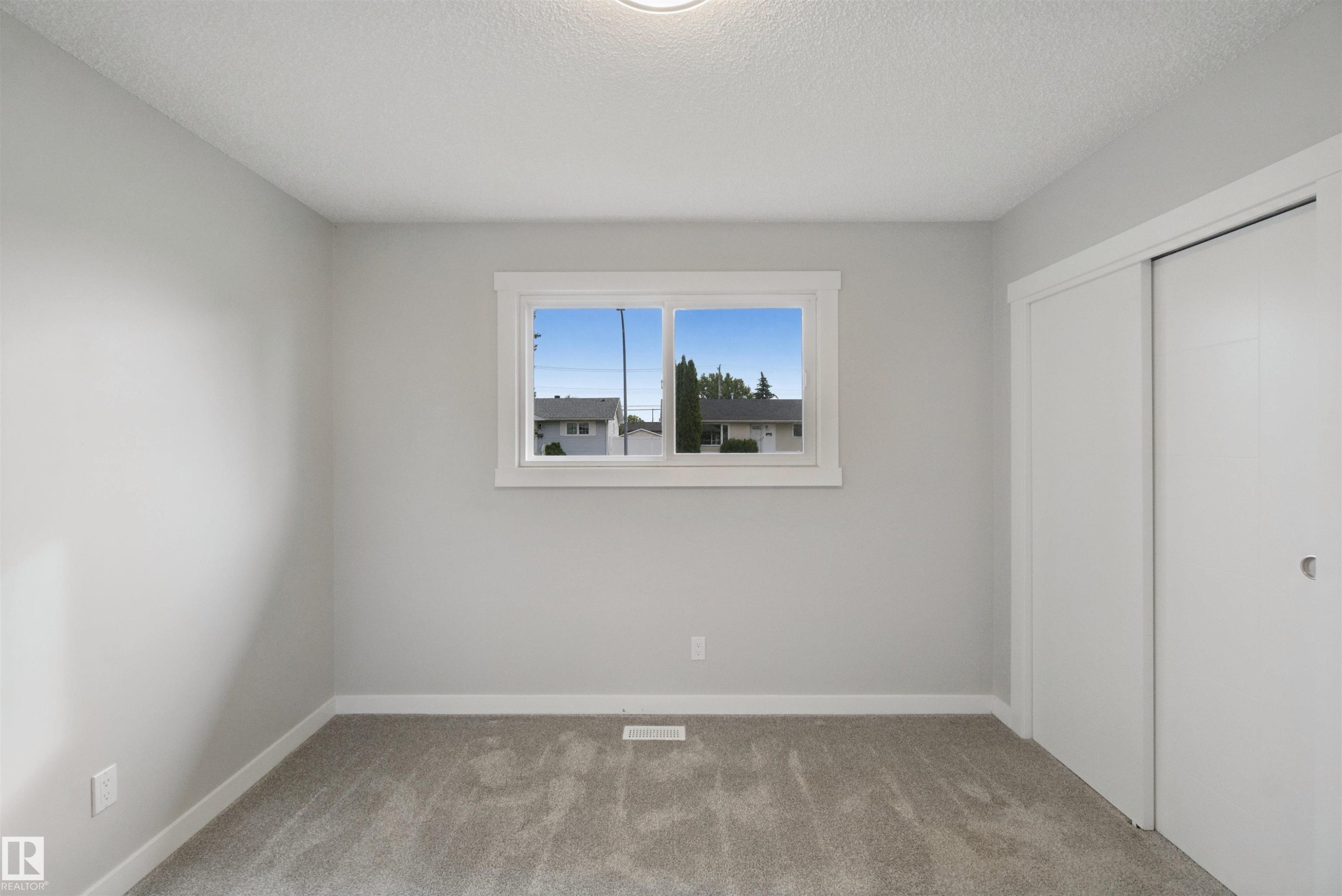 Light gray wall paint, white trim, gray carpeting, single window, and sliding closet doors - 13212 73 Street Nw, Edmonton, AB