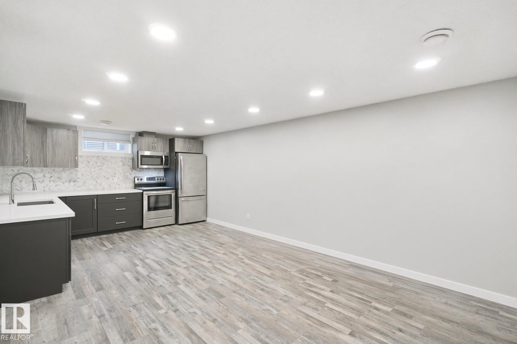 Kitchenette with stainless steel appliances, wood-finish flooring, recessed lighting, and a white countertop - 13212 73 Street Nw, Edmonton, AB