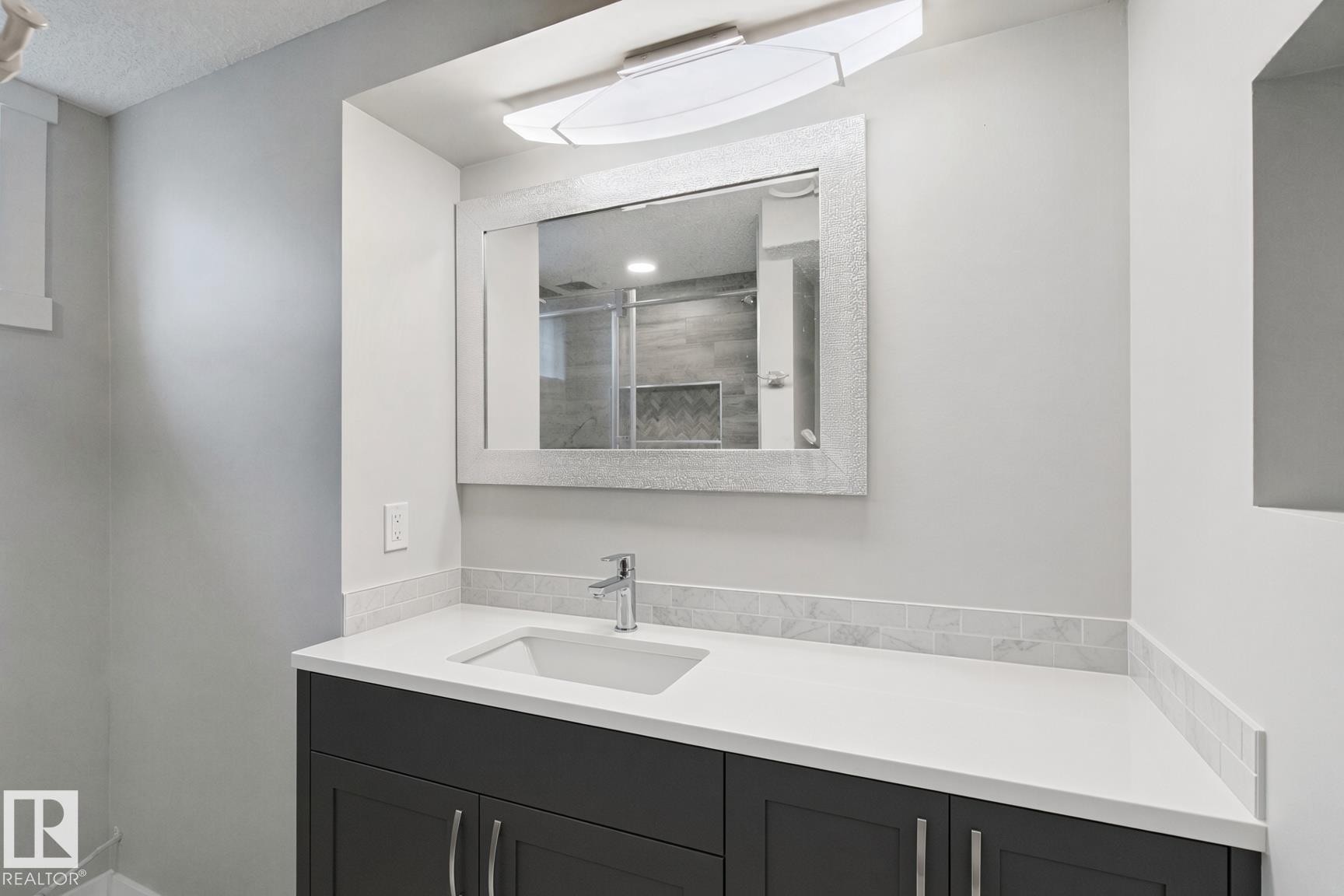 Vanity featuring a white countertop with an integrated sink, polished chrome faucet, and dark wood-finish cabinetry - 13212 73 Street Nw, Edmonton, AB