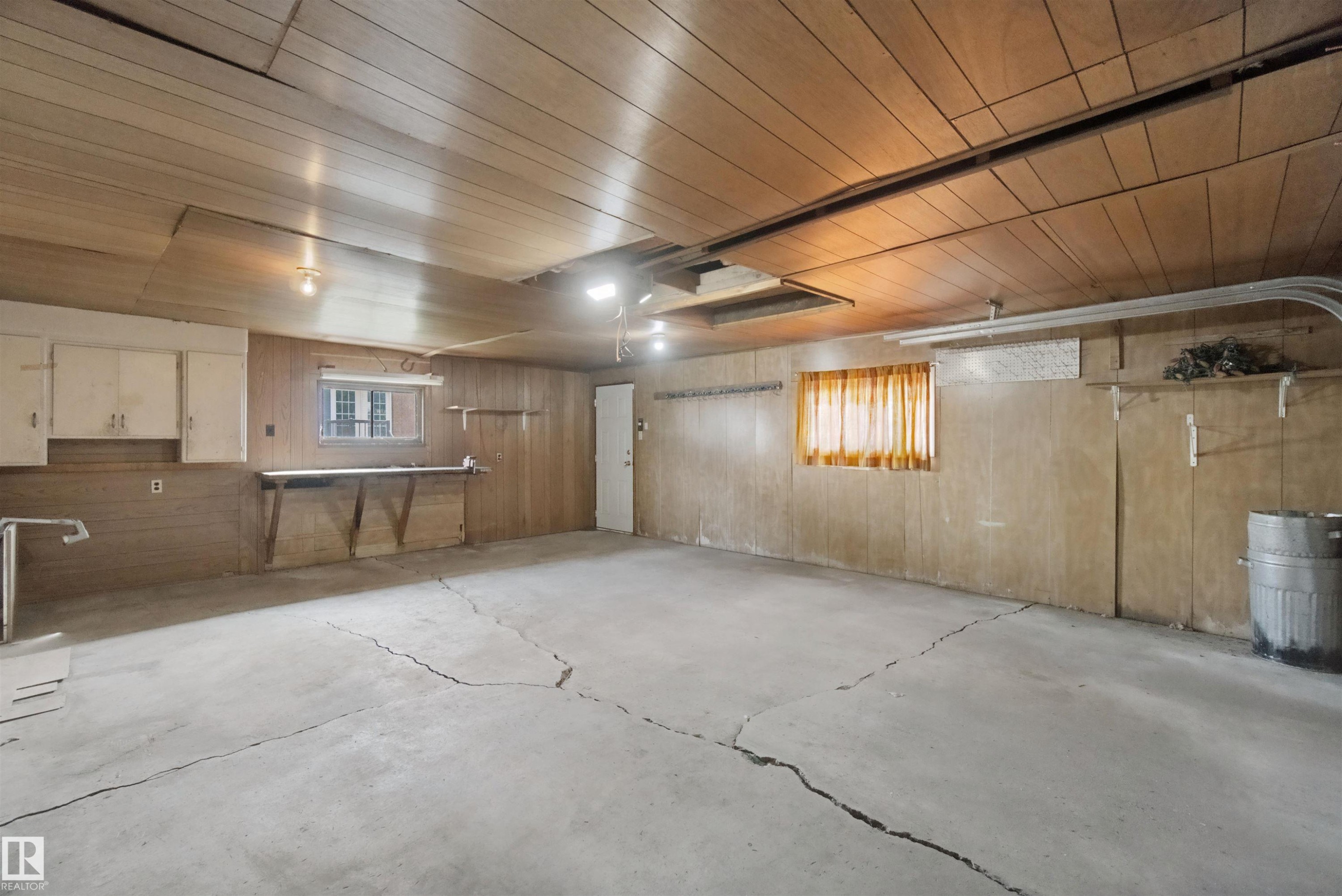 Concrete flooring, wood paneling, built-in cabinetry, overhead lighting, window - 13212 73 Street Nw, Edmonton, AB