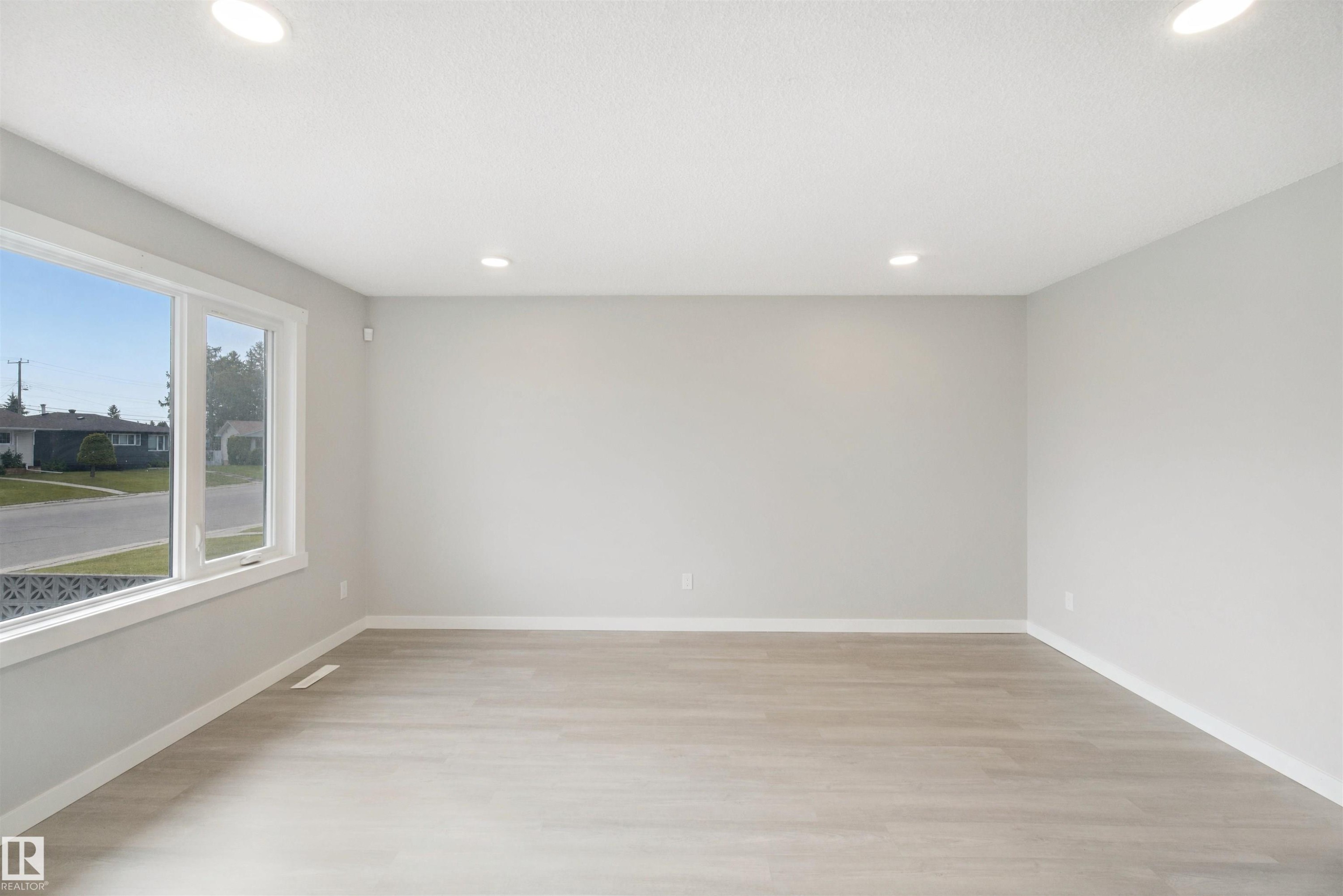 Expansive room featuring wood-finish flooring, recessed ceiling lighting, and large windows with white trim - 13212 73 Street Nw, Edmonton, AB