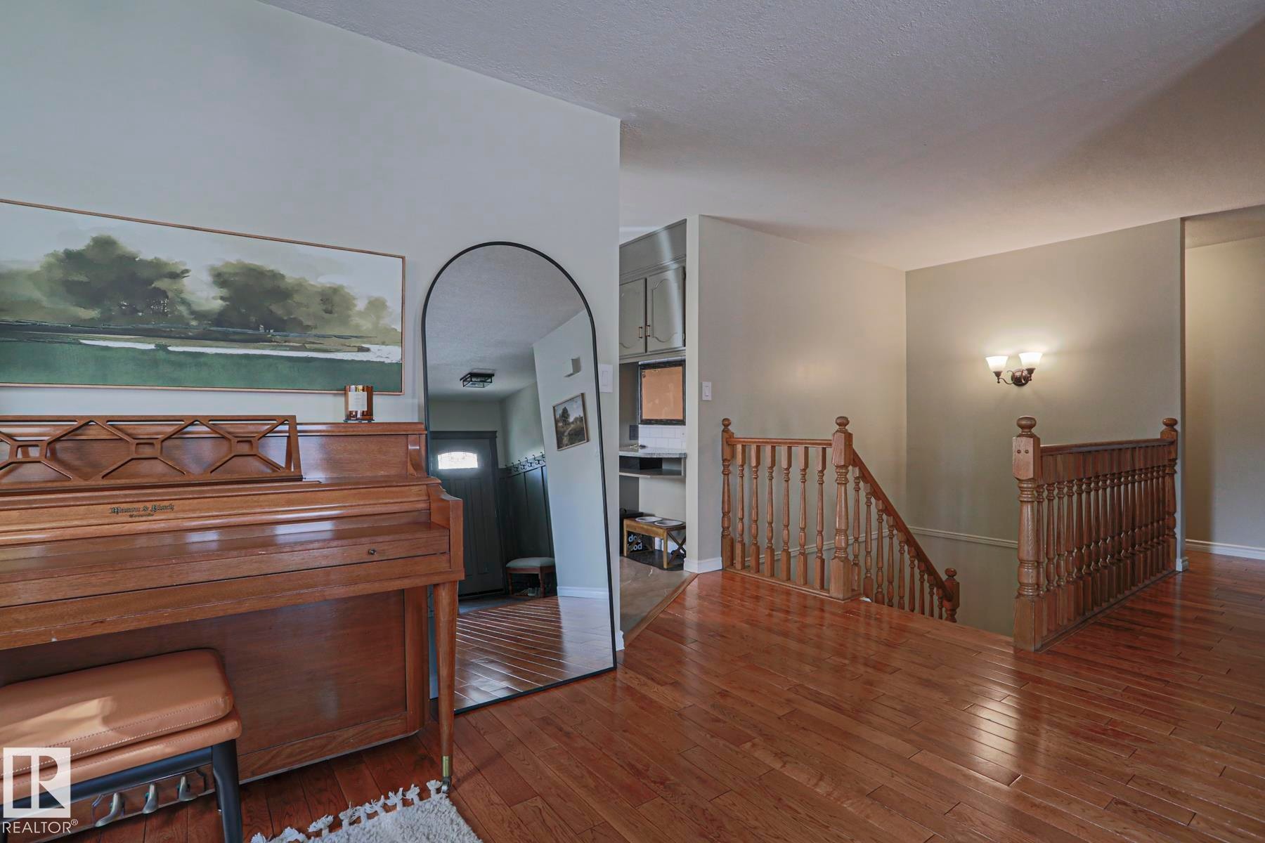Wood-finish flooring throughout, solid wood stair railing, and a wall-mounted light fixture - 2 Hillview Crescent, Sherwood Park, AB