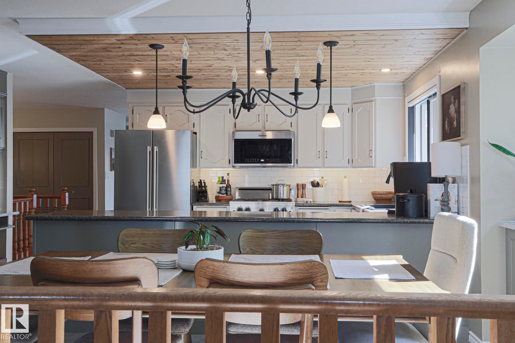 Kitchen featuring shaker-style cabinetry, stainless steel appliances, a subway tile backsplash, and a wood-paneled ceiling - 2 Hillview Crescent, Sherwood Park, AB