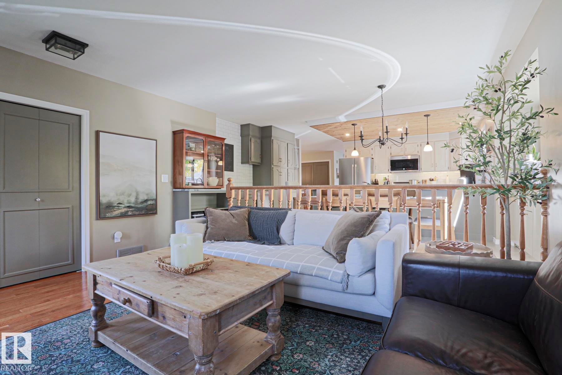 Wood-finish flooring, wood balustrade, recessed lighting, chandelier, and a wood-finish coffee table - 2 Hillview Crescent, Sherwood Park, AB