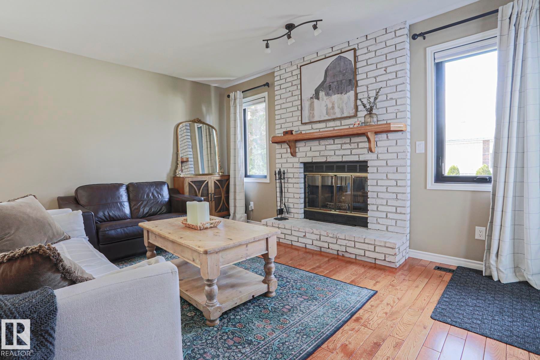 Brick fireplace with a wood mantle, wood-finish flooring, and recessed lighting - 2 Hillview Crescent, Sherwood Park, AB