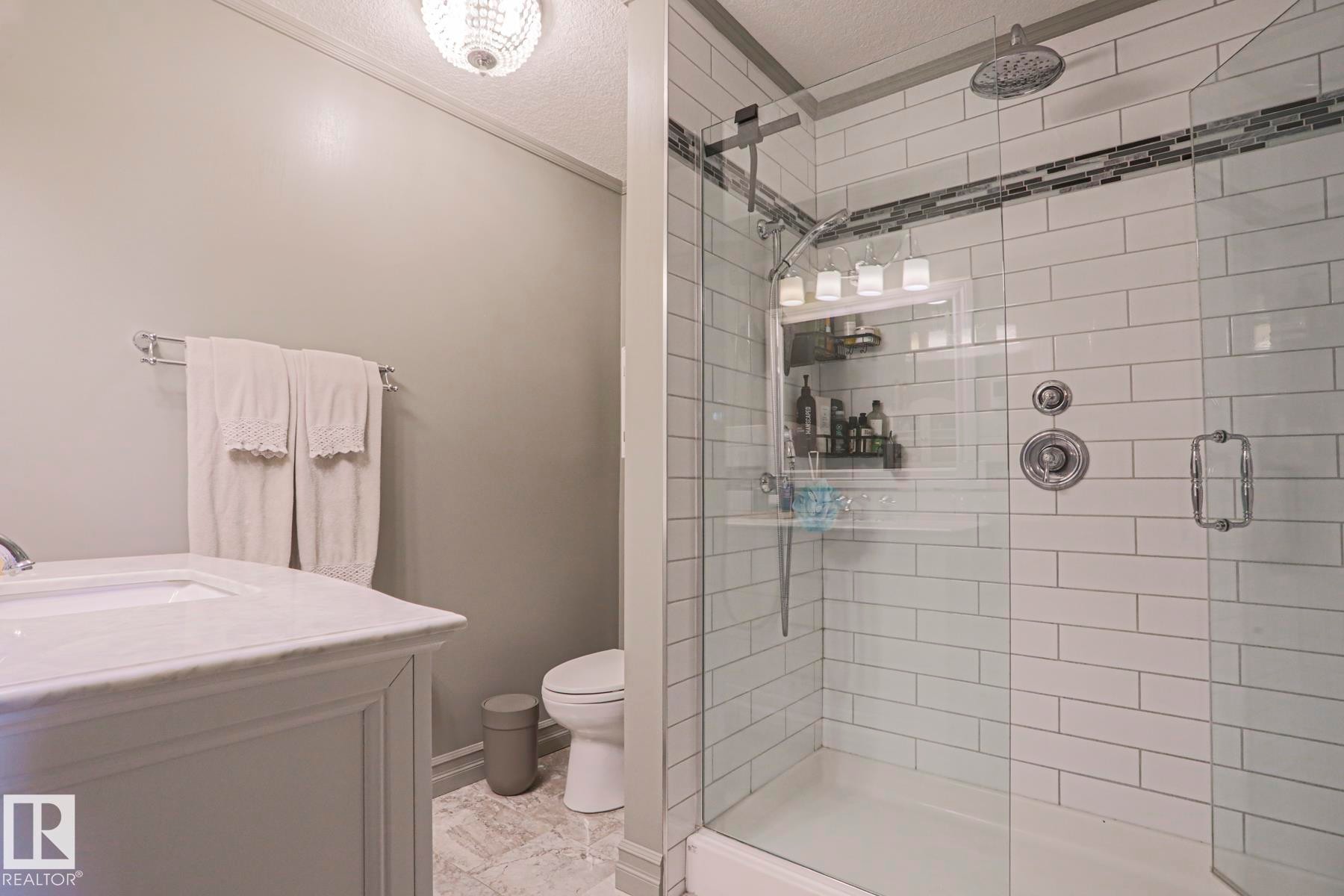 Walk-in shower with subway tile surround, integrated mosaic tile accent, and glass enclosure - 2 Hillview Crescent, Sherwood Park, AB