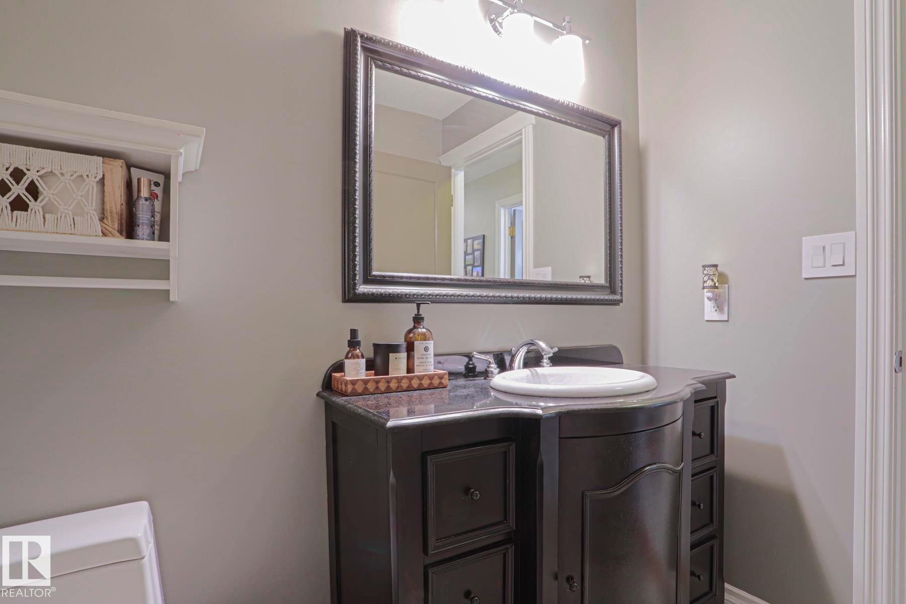 Dark wood vanity with an integral sink, chrome faucet, and a framed mirror - 2 Hillview Crescent, Sherwood Park, AB