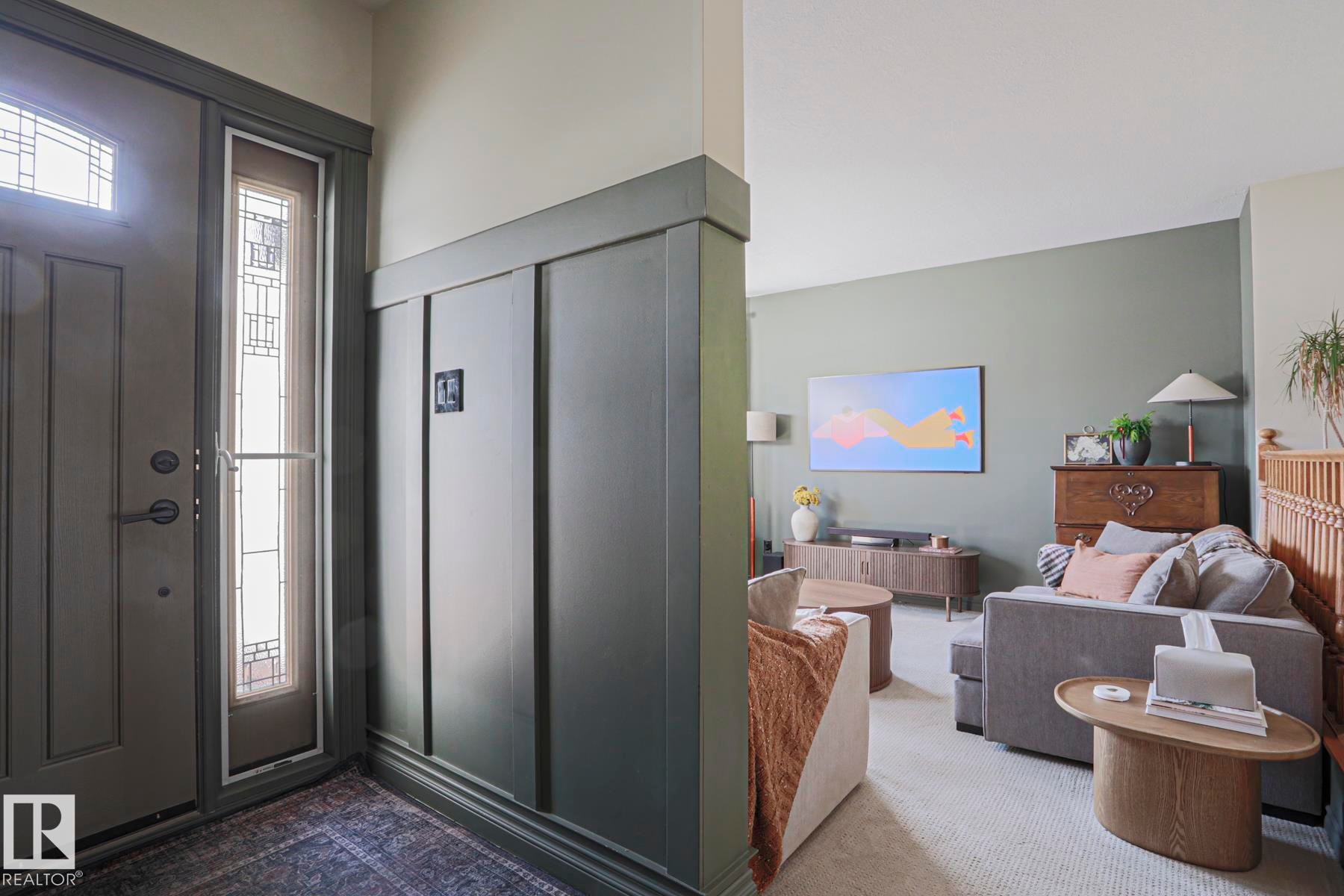 Entryway featuring a decorative front door with transom and sidelight, board and batten wall paneling, and a warm color palette - 2 Hillview Crescent, Sherwood Park, AB