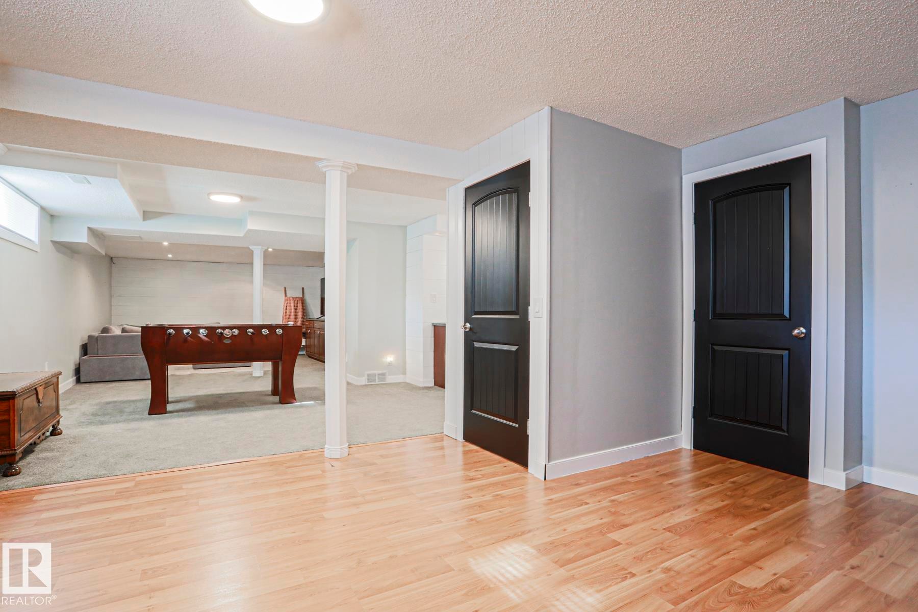 Wood-finish flooring, light gray wall paint, white baseboards, and black panel doors - 2 Hillview Crescent, Sherwood Park, AB