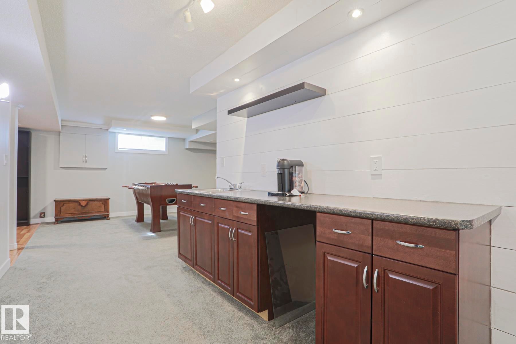 Wet bar with dark wood cabinetry, light-toned countertop, and stainless steel sink - 2 Hillview Crescent, Sherwood Park, AB