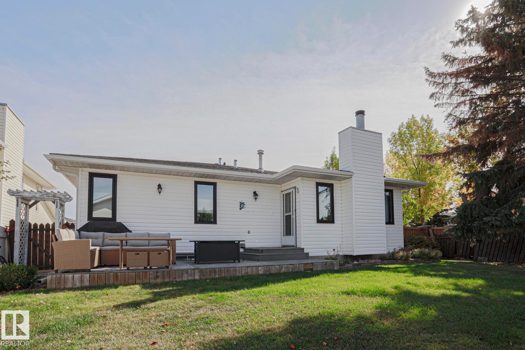 Expansive backyard featuring a manicured lawn, a multi-level deck, and a white pergola - 2 Hillview Crescent, Sherwood Park, AB