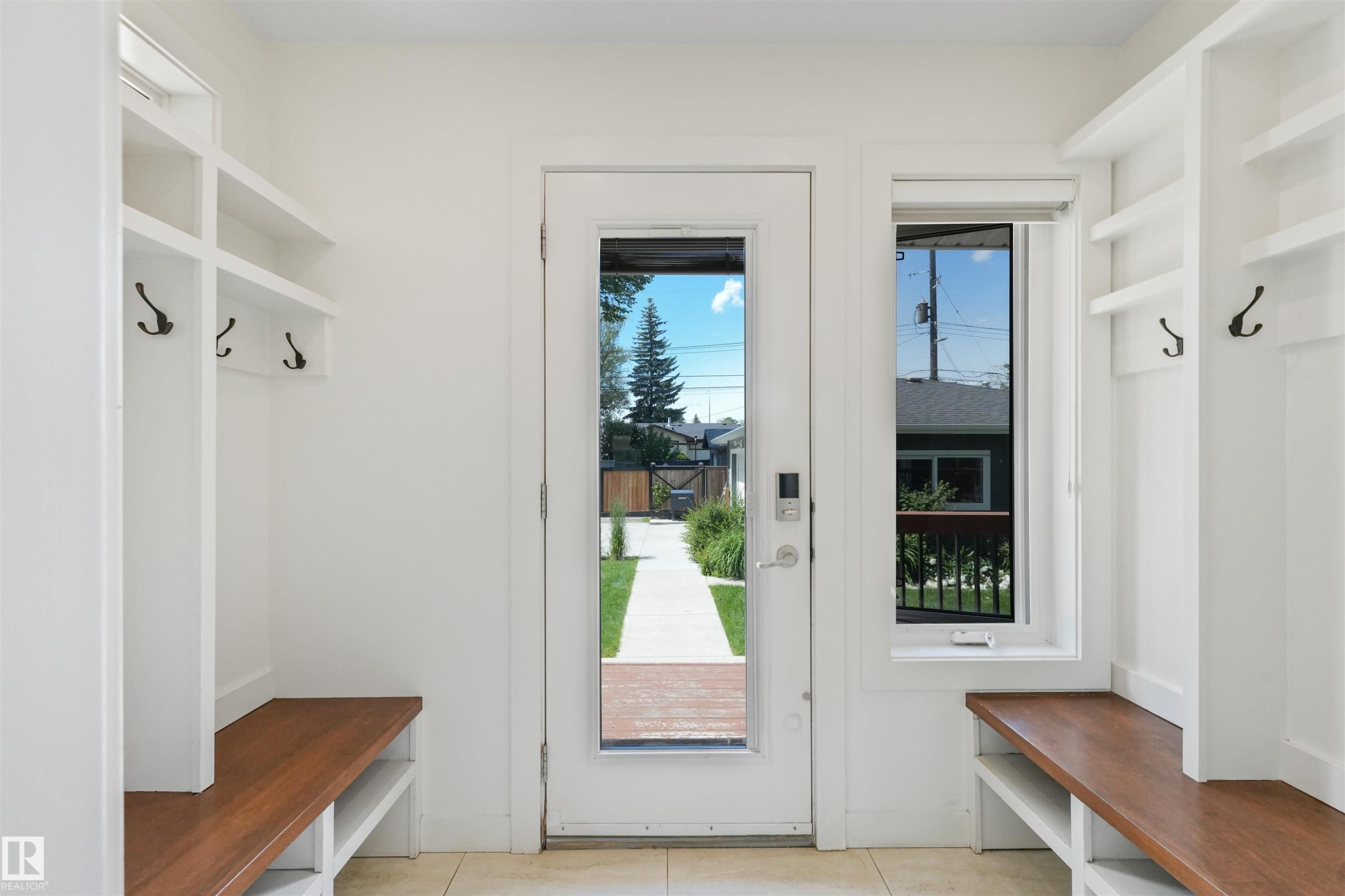 Entryway featuring built-in white cabinetry, integrated wood-finish benches, and dark metal coat hooks - 8212 148 Street Nw, Edmonton, AB