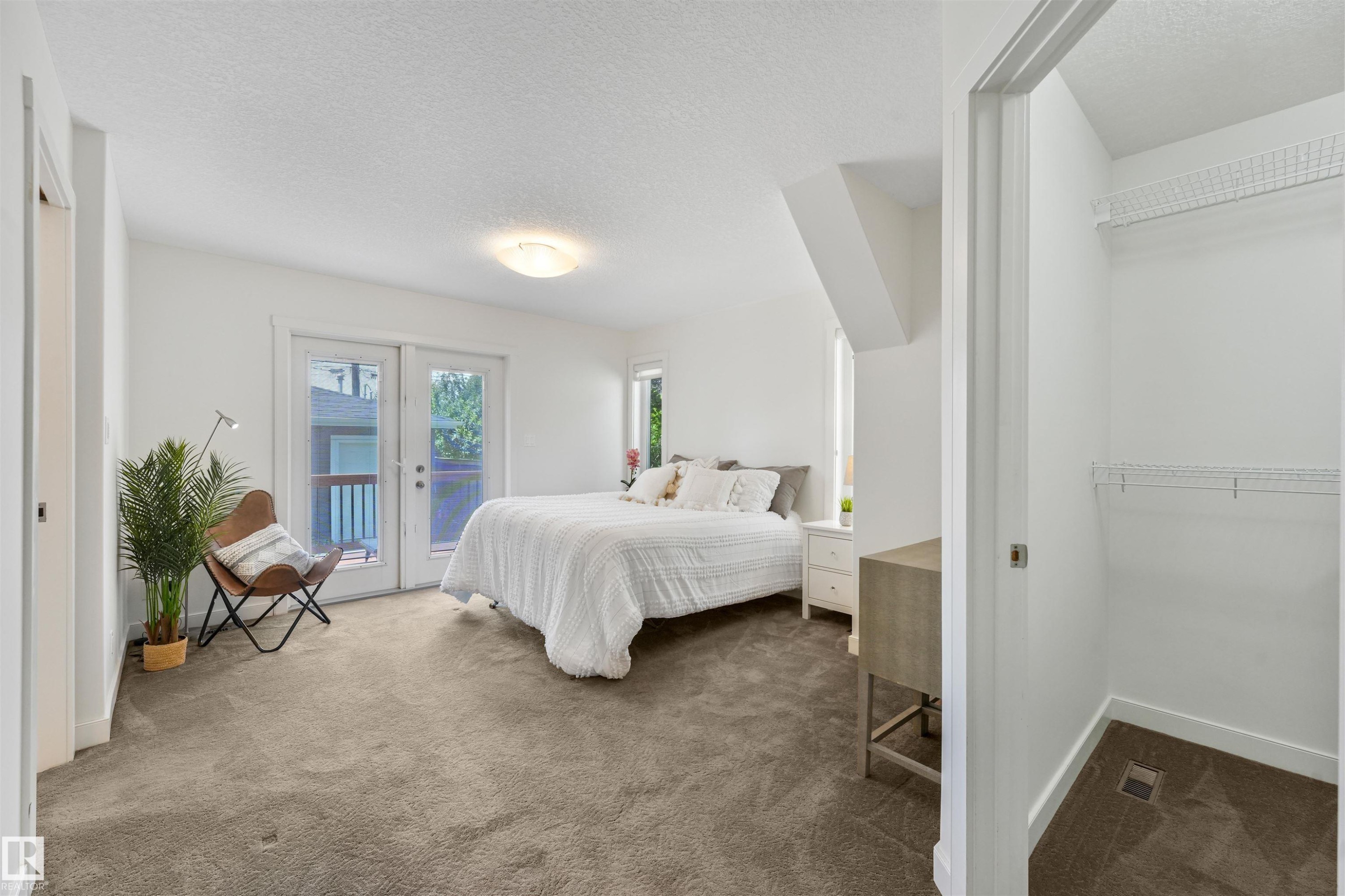 White walls, carpet flooring, a built-in closet with wire shelving, and double French patio doors - 8212 148 Street Nw, Edmonton, AB