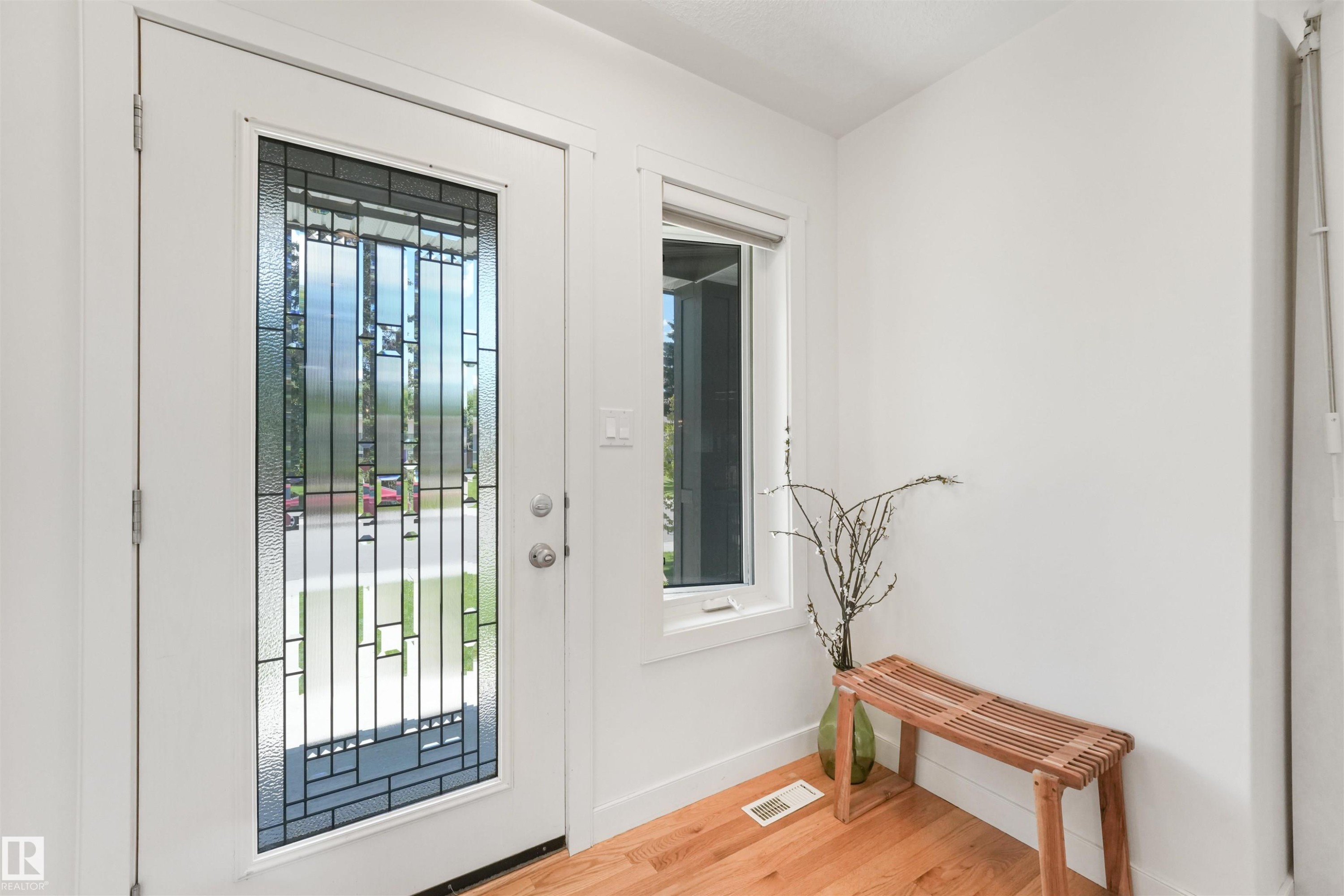Entryway featuring a decorative glass panel door, a side light window, and wood-finish flooring - 8212 148 Street Nw, Edmonton, AB