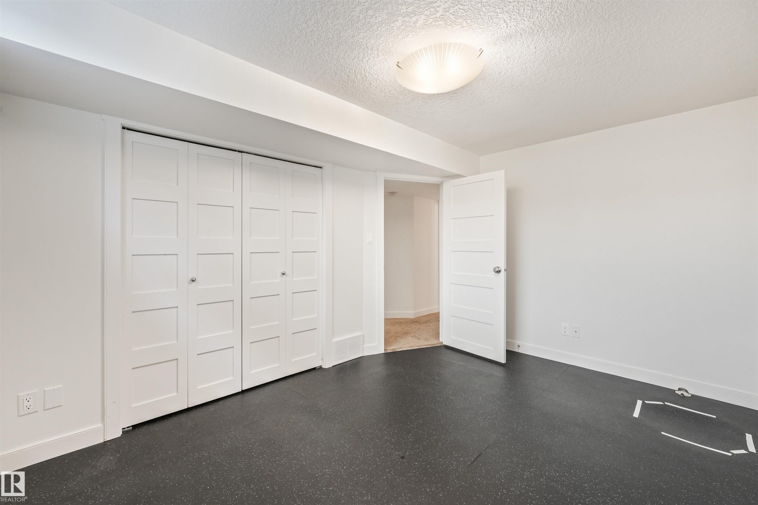 White paneled bifold closet doors, interior paneled door, flush-mount ceiling light fixture, and dark flooring - 8212 148 Street Nw, Edmonton, AB
