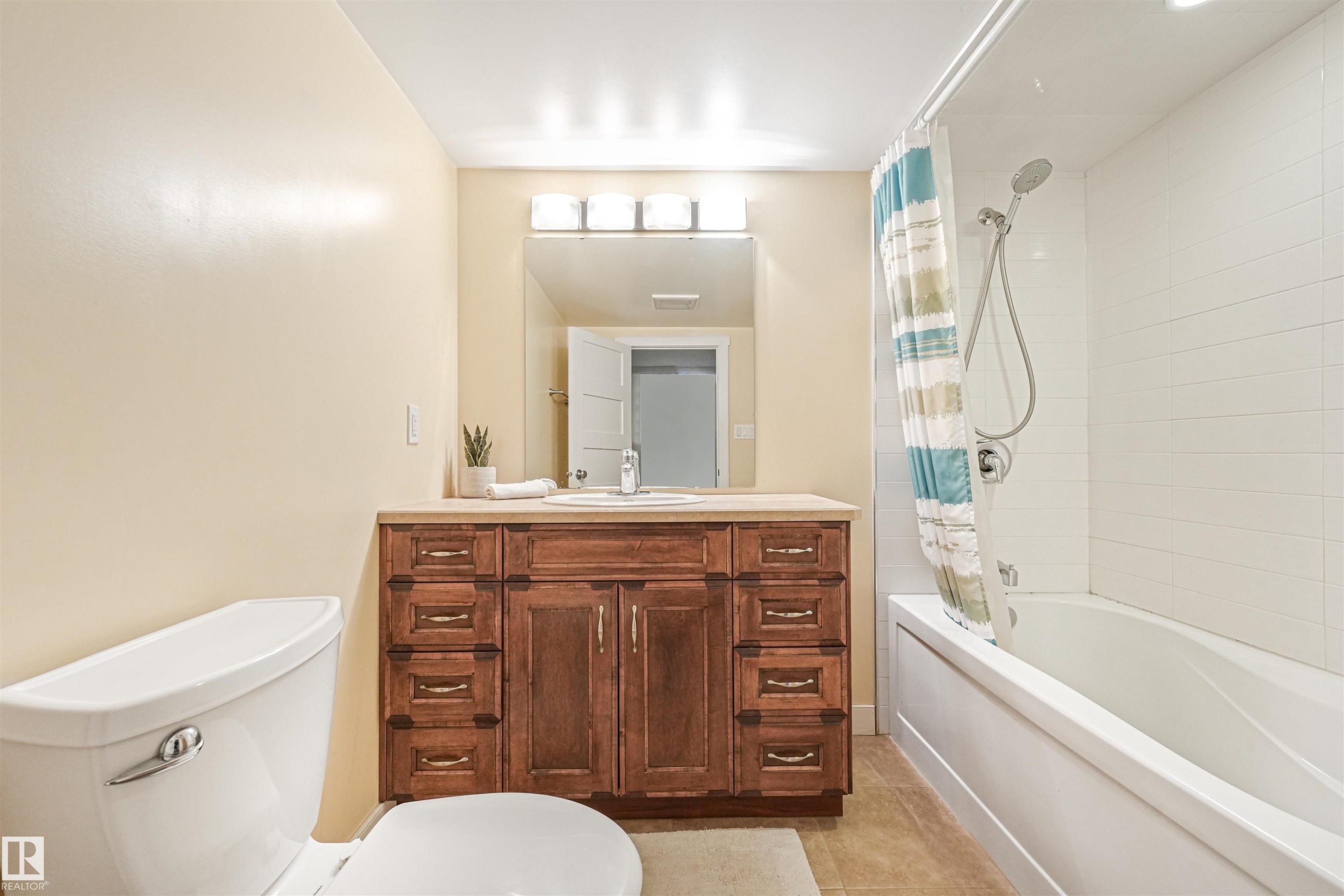 Wood-finish vanity with an integrated sink, broad mirror, and overhead light bar - 8212 148 Street Nw, Edmonton, AB