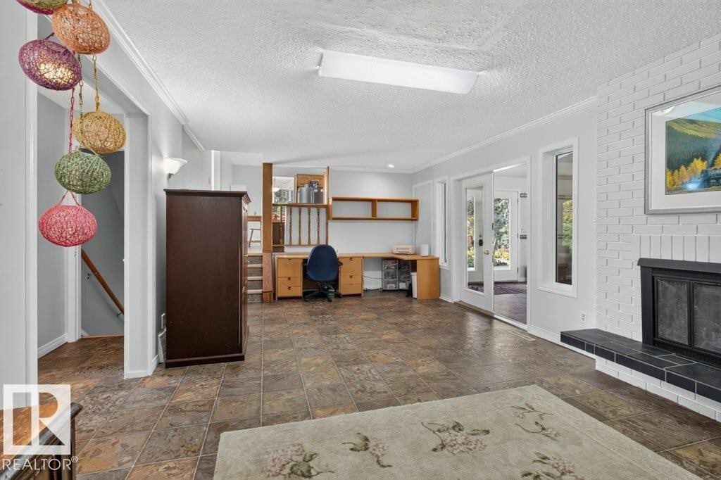 Spacious interior featuring a white brick fireplace with a black hearth, built-in shelving, and large sliding glass doors - #74 22555 Twp Road 530, Rural Strathcona County, AB