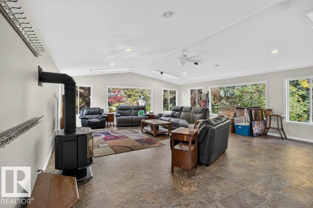 Spacious living area featuring large windows, a ceiling fan, recessed lighting, and a freestanding stove with a flue - #74 22555 Twp Road 530, Rural Strathcona County, AB