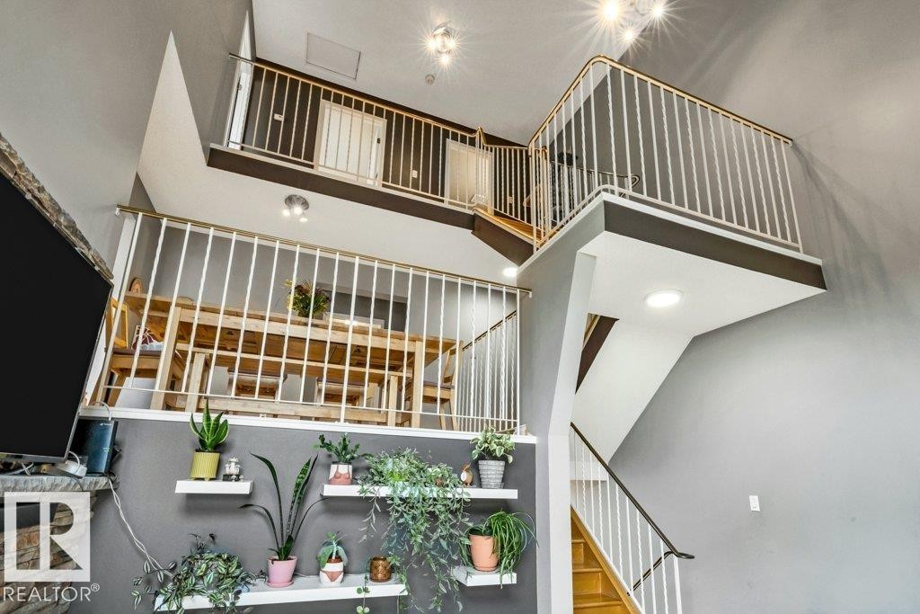 Multi-level interior featuring open railings, recessed lighting, wood-finish stairs, and a stone-clad fireplace - #24 3811 85 St Nw, Edmonton, AB