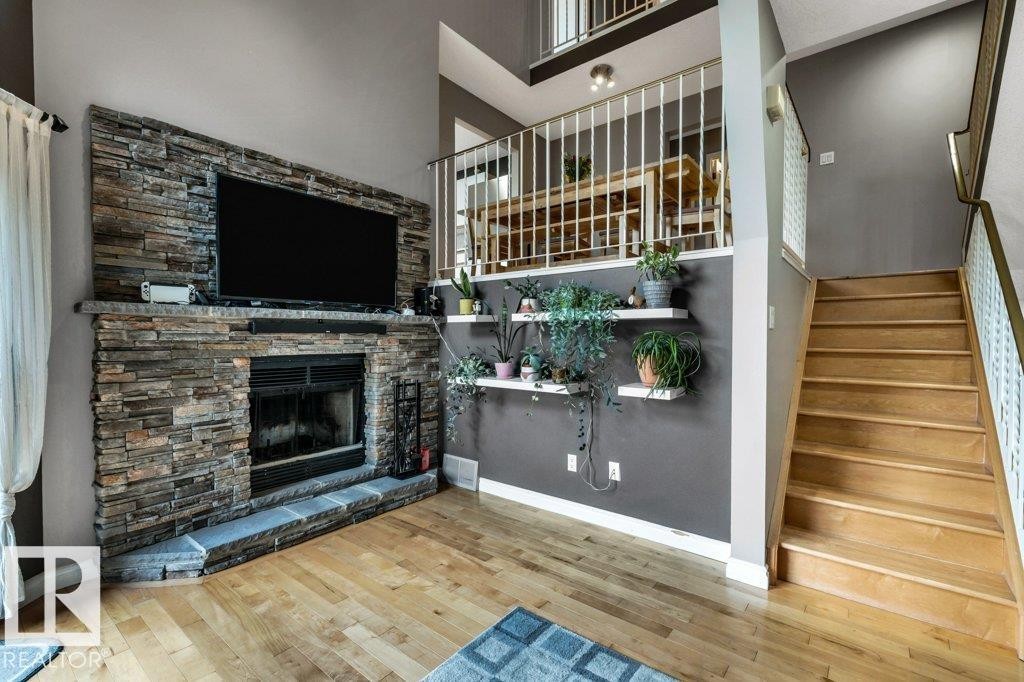 Wood-finish flooring with a stacked stone fireplace featuring a hearth - #24 3811 85 St Nw, Edmonton, AB
