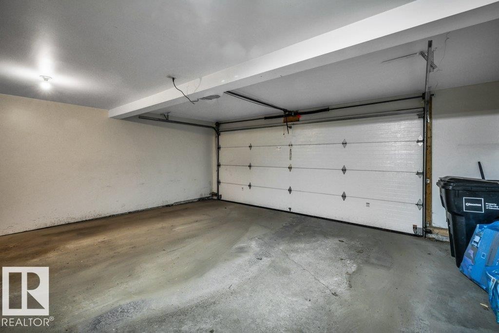 Attached garage with concrete flooring and a white sectional garage door - #24 3811 85 St Nw, Edmonton, AB